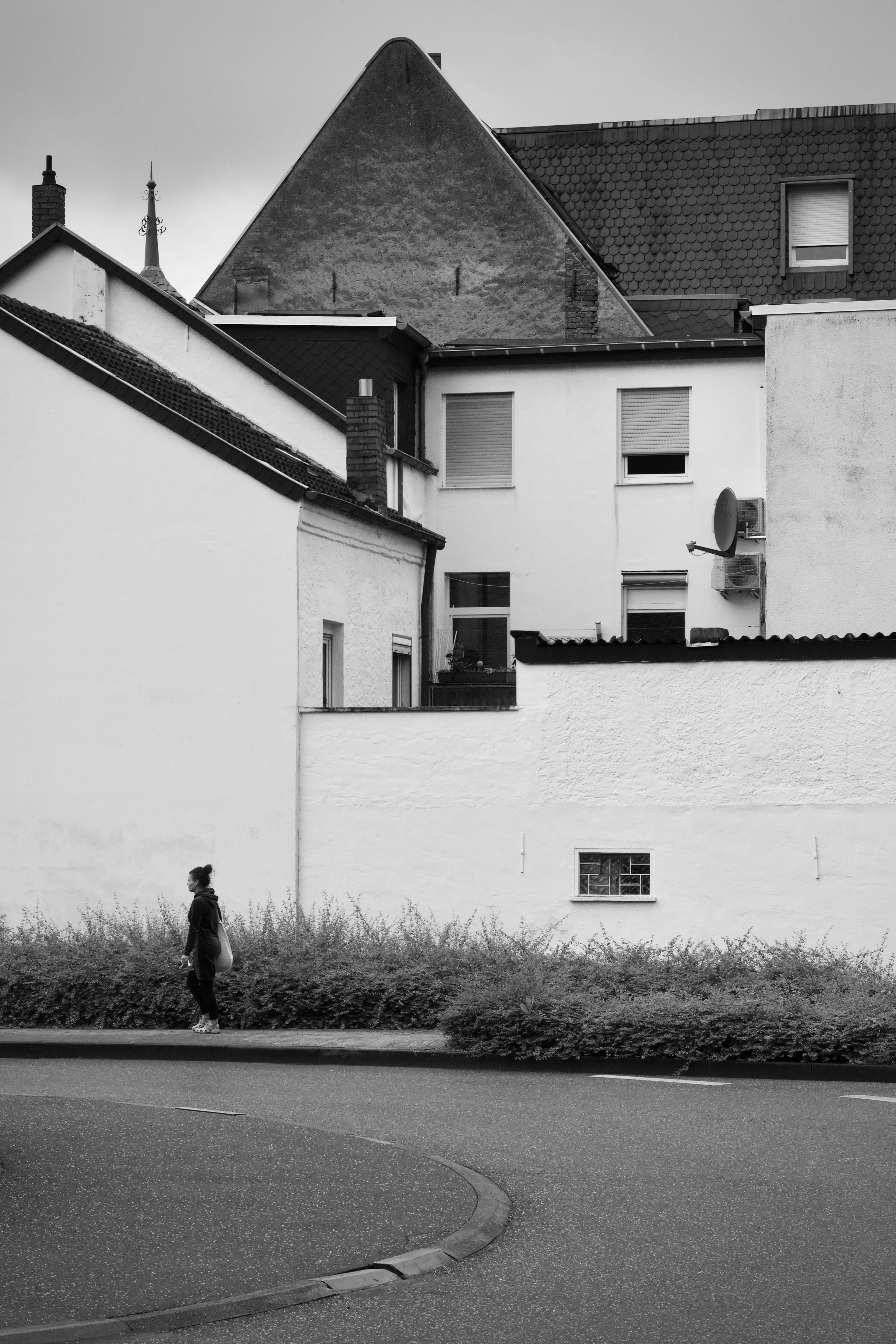 Gratis In questa classica foto in bianco e nero, una figura solitaria cammina tra gli edifici urbani. Foto a disposizione