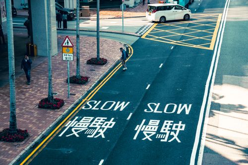 Free Street intersection with 'Slow' text in English and Chinese, featuring pedestrians and vehicles. Stock Photo
