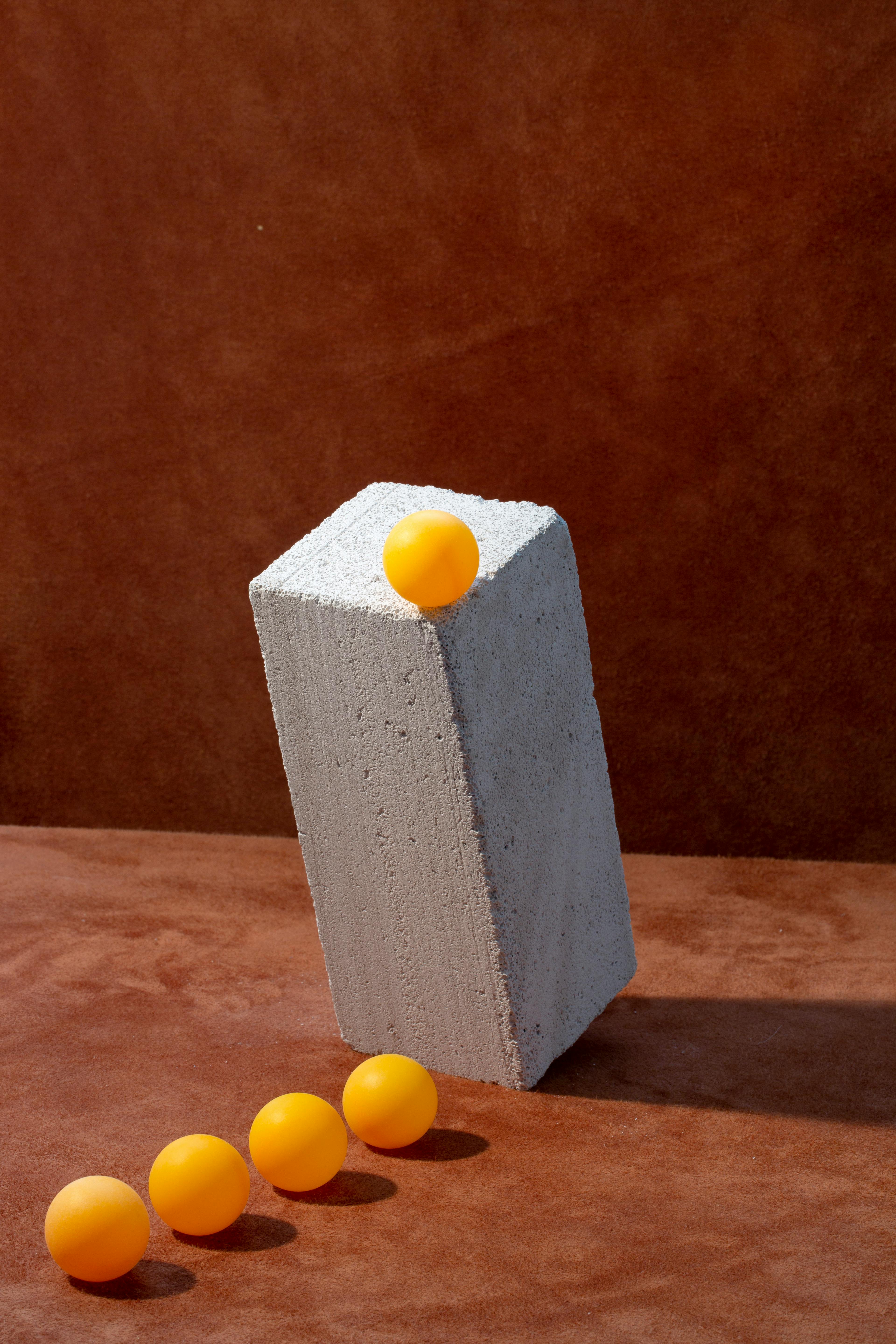 Gratuit Bile portocalii aranjate cu un bloc de beton, creând o compoziție abstractă modernă Fotografie de stoc