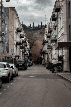 View of a serene urban street lined with historic buildings and parked cars, ideal for city and travel themes.