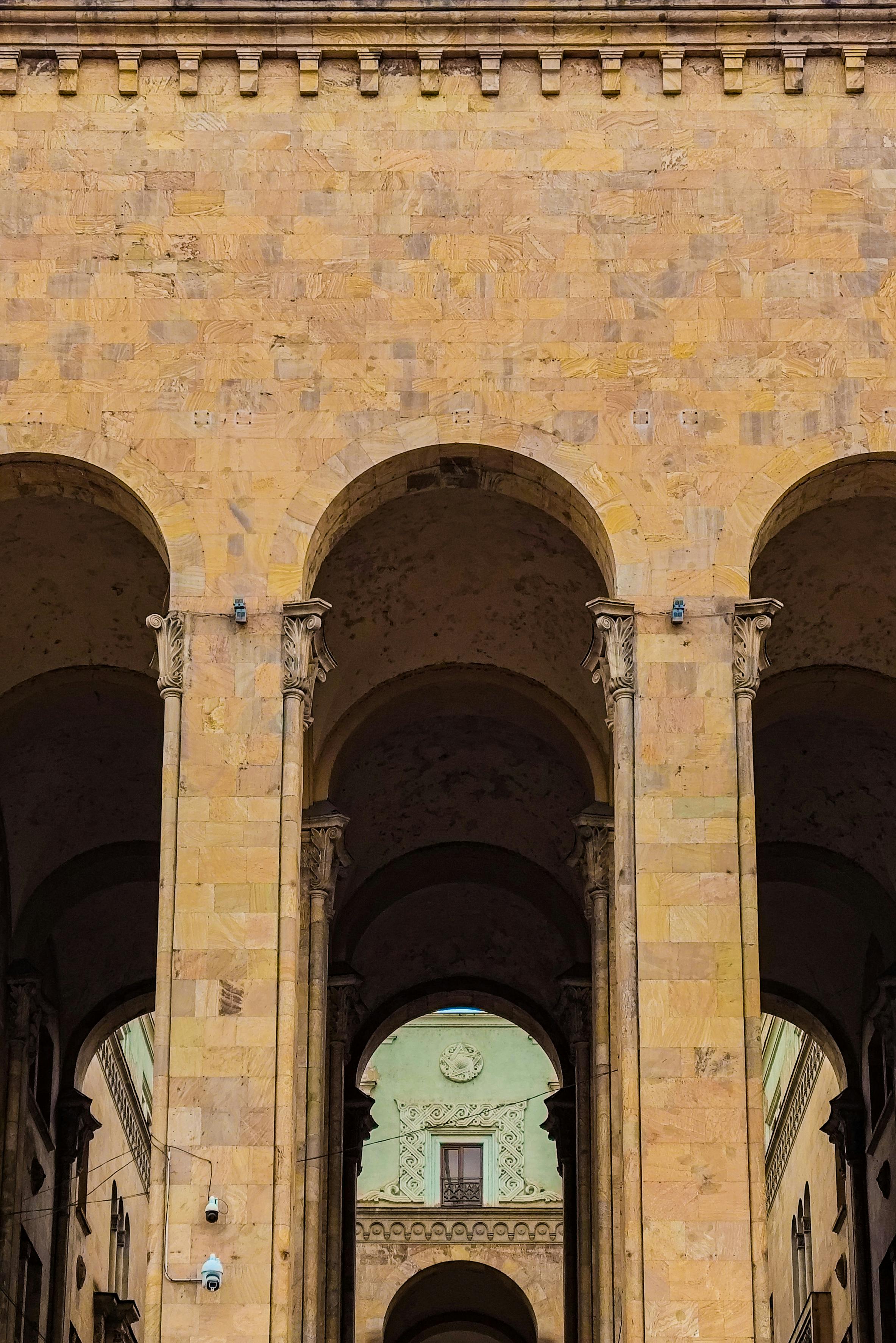 Gratis Un maestoso arco in pietra con colonne intricate in un paesaggio urbano. Foto a disposizione