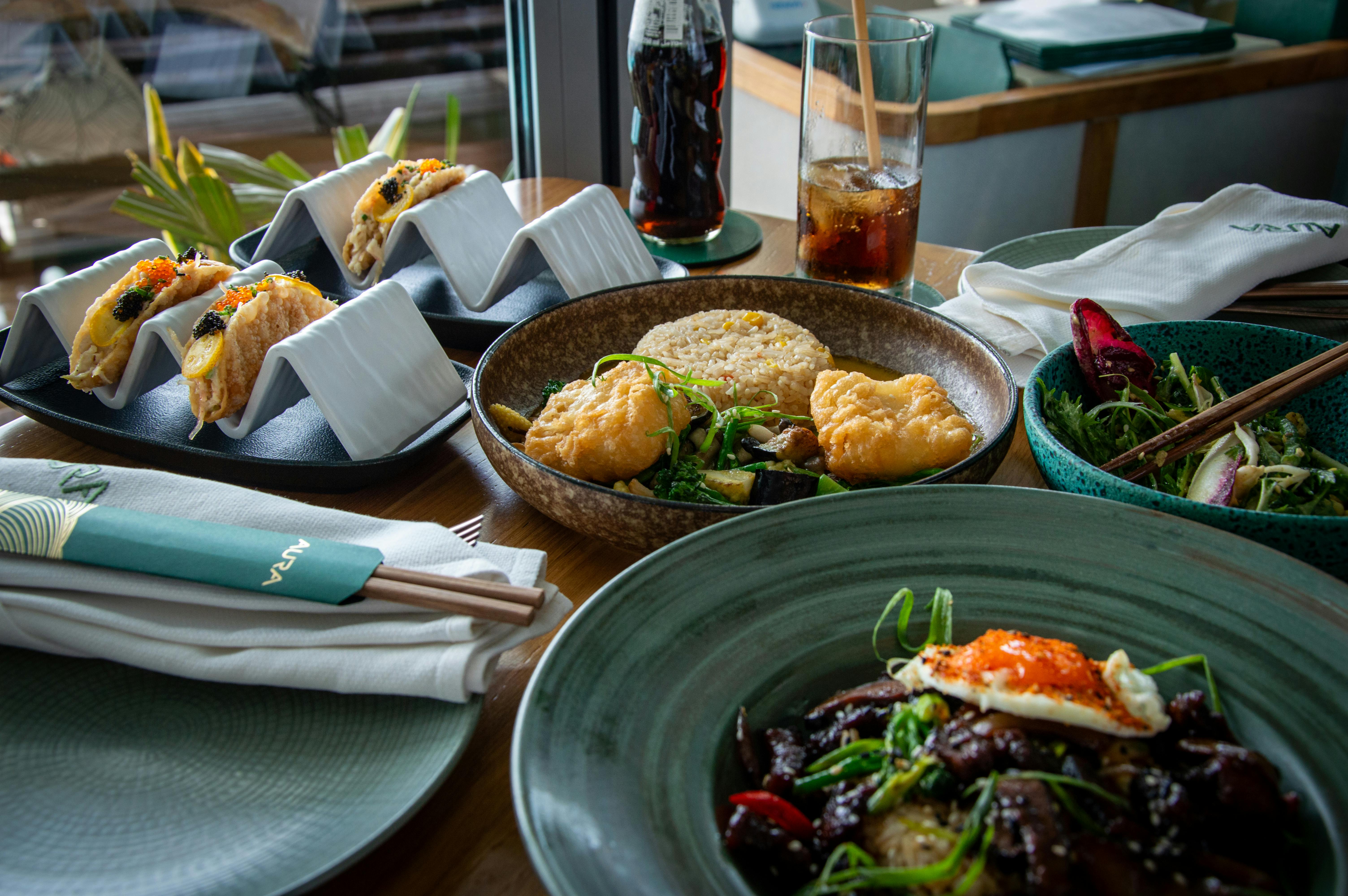 Gratis Una varietà di piatti fusion asiatici serviti sul tavolo di un ristorante, che mettono in risalto colori e consistenze vivaci. Foto a disposizione