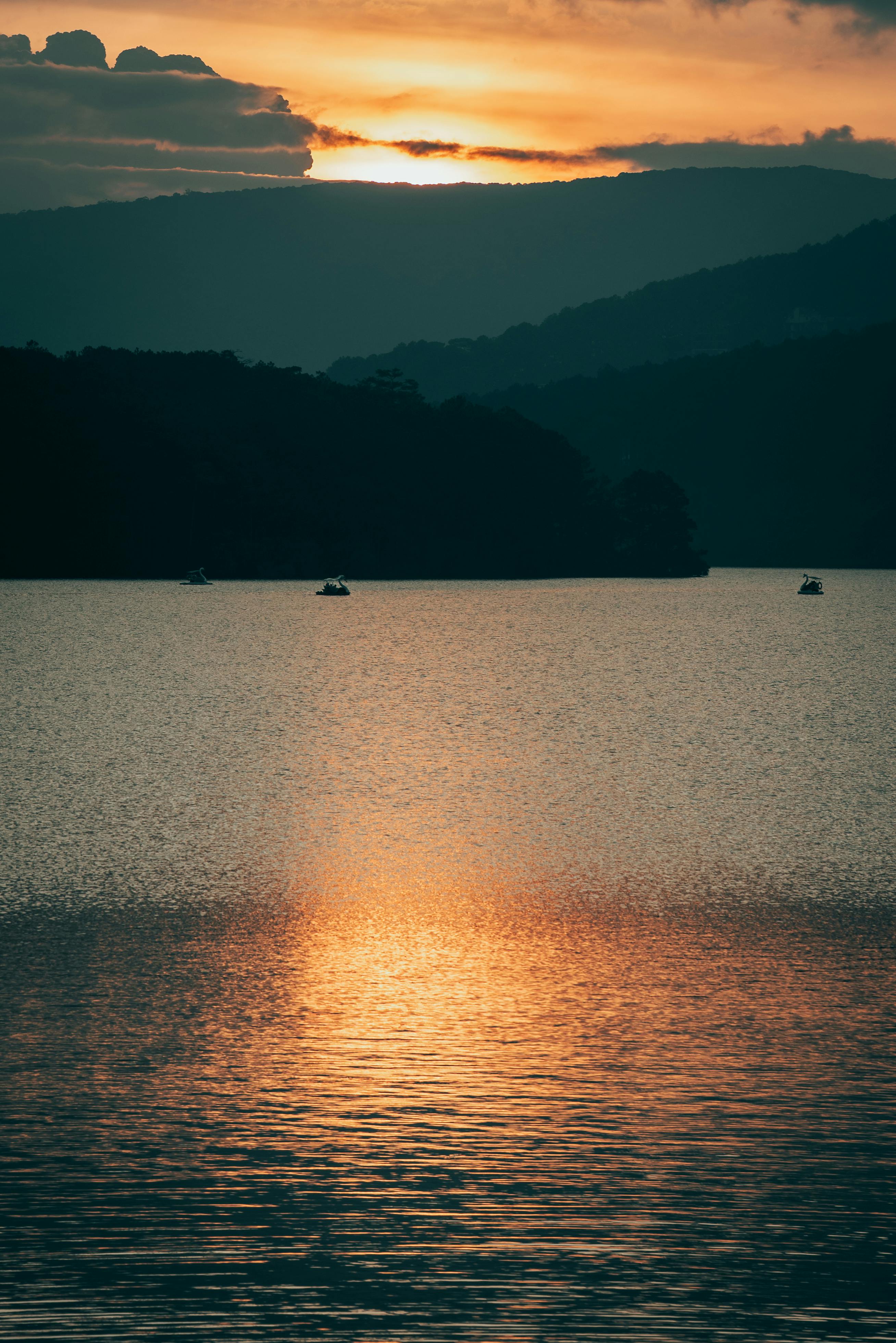 Gratis Vista tranquilla sul lago con tramonto vibrante sulle montagne. Foto a disposizione