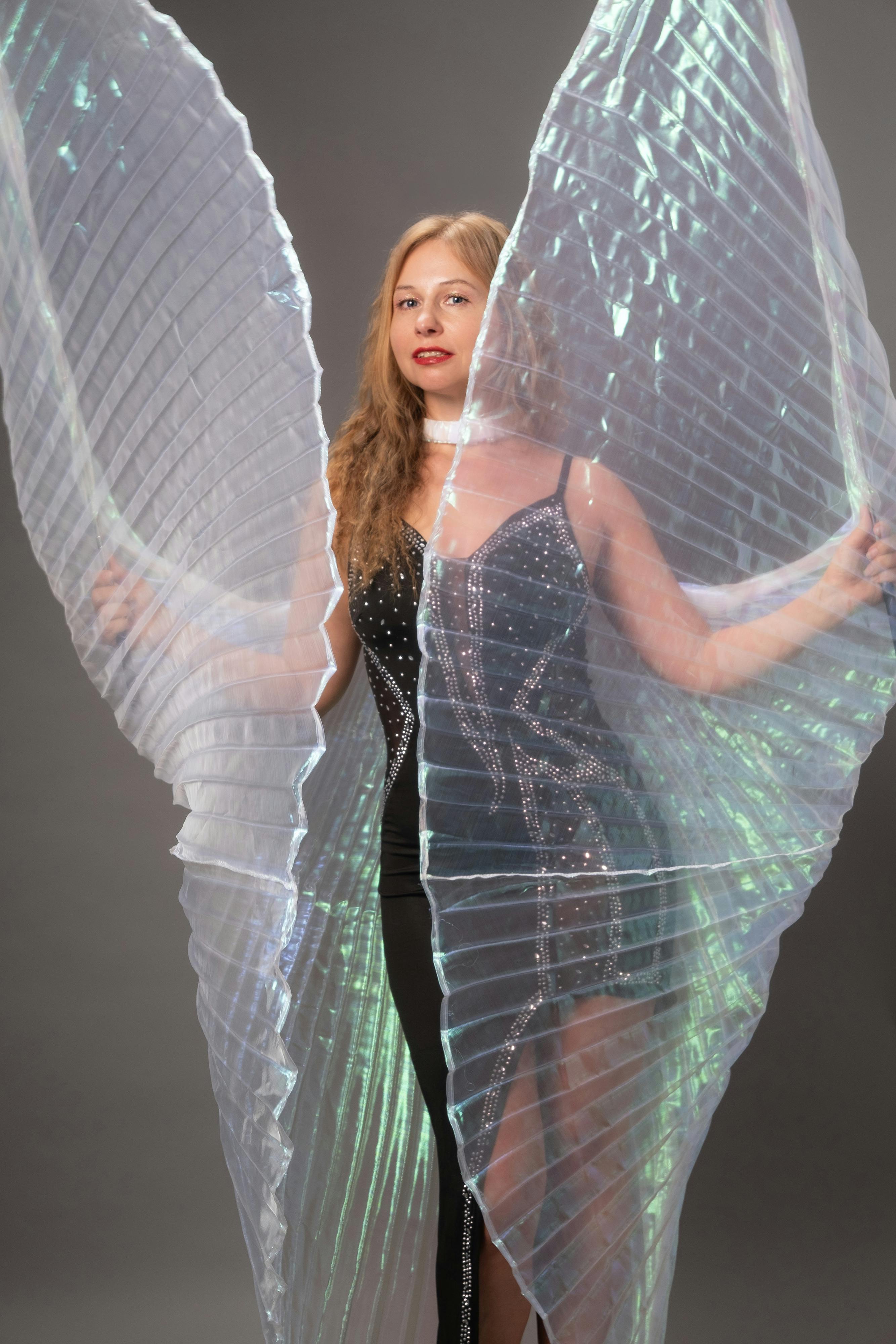 Gratis Donna che posa con ali iridescenti in uno studio, mostrando eleganza e glamour. Foto a disposizione