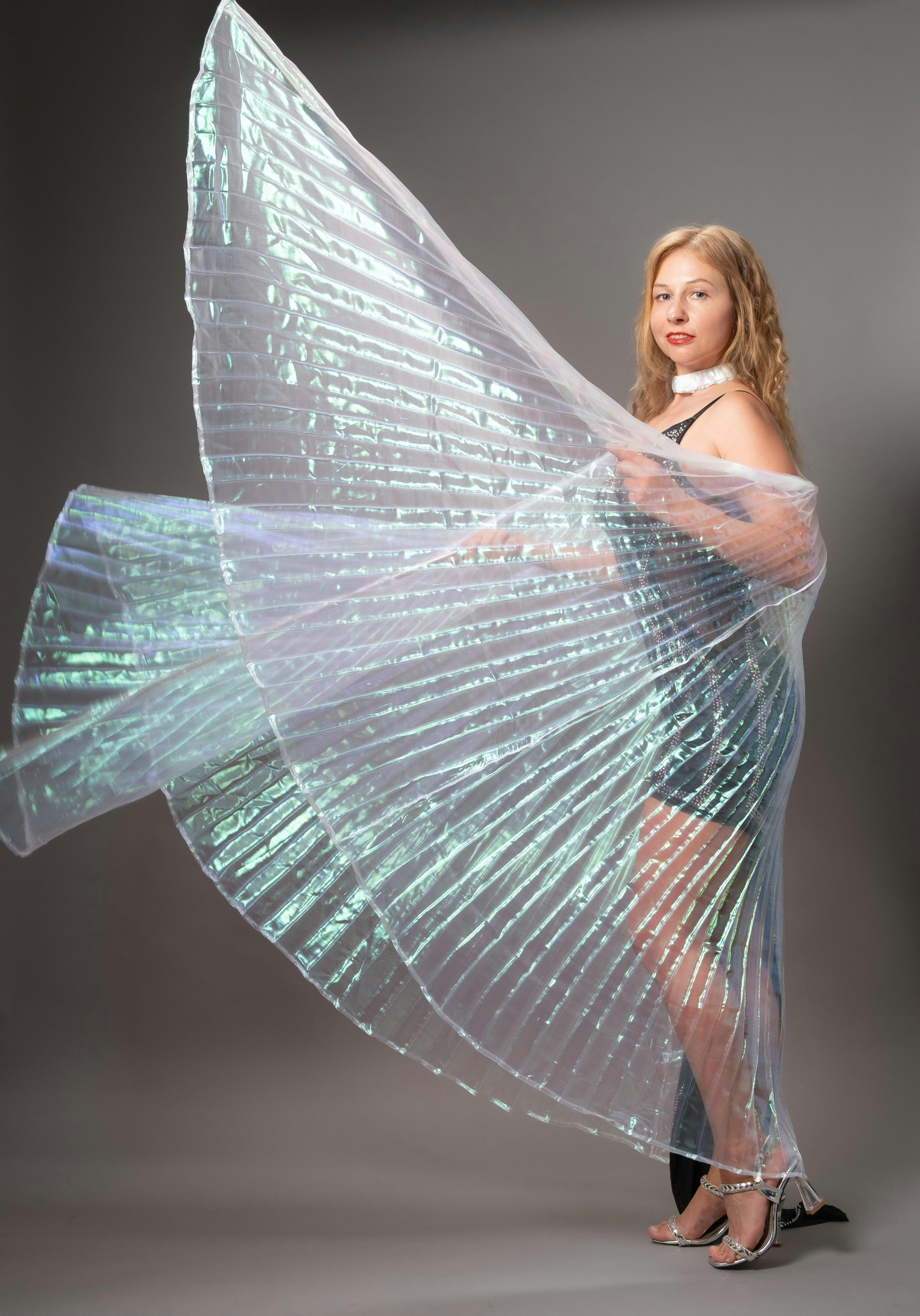 Gratis Donna in posa con un abito scintillante dal tessuto fluido, elegante e alla moda. Foto a disposizione