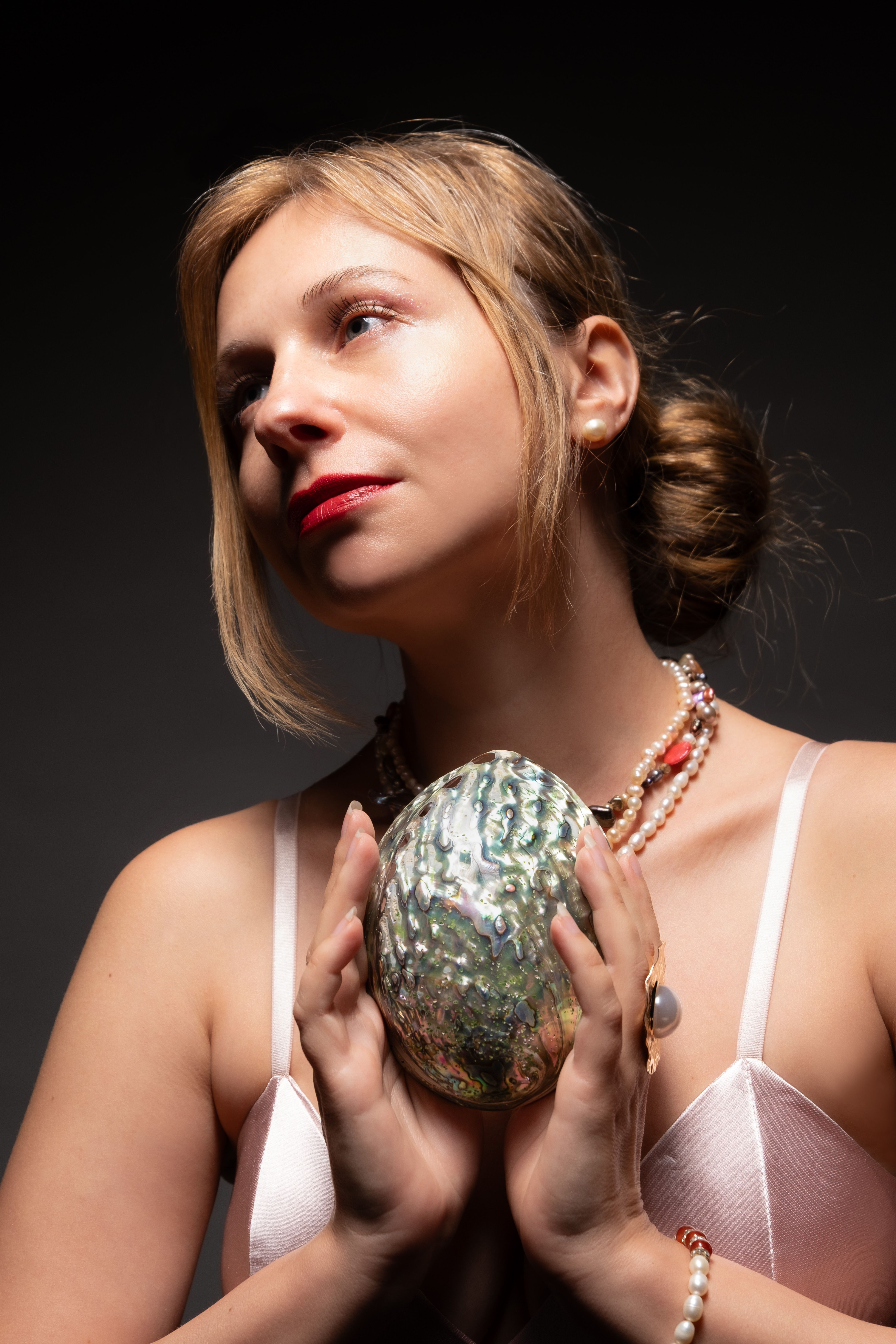 Artistic portrait of a woman holding a shell, showcasing elegance and beauty.