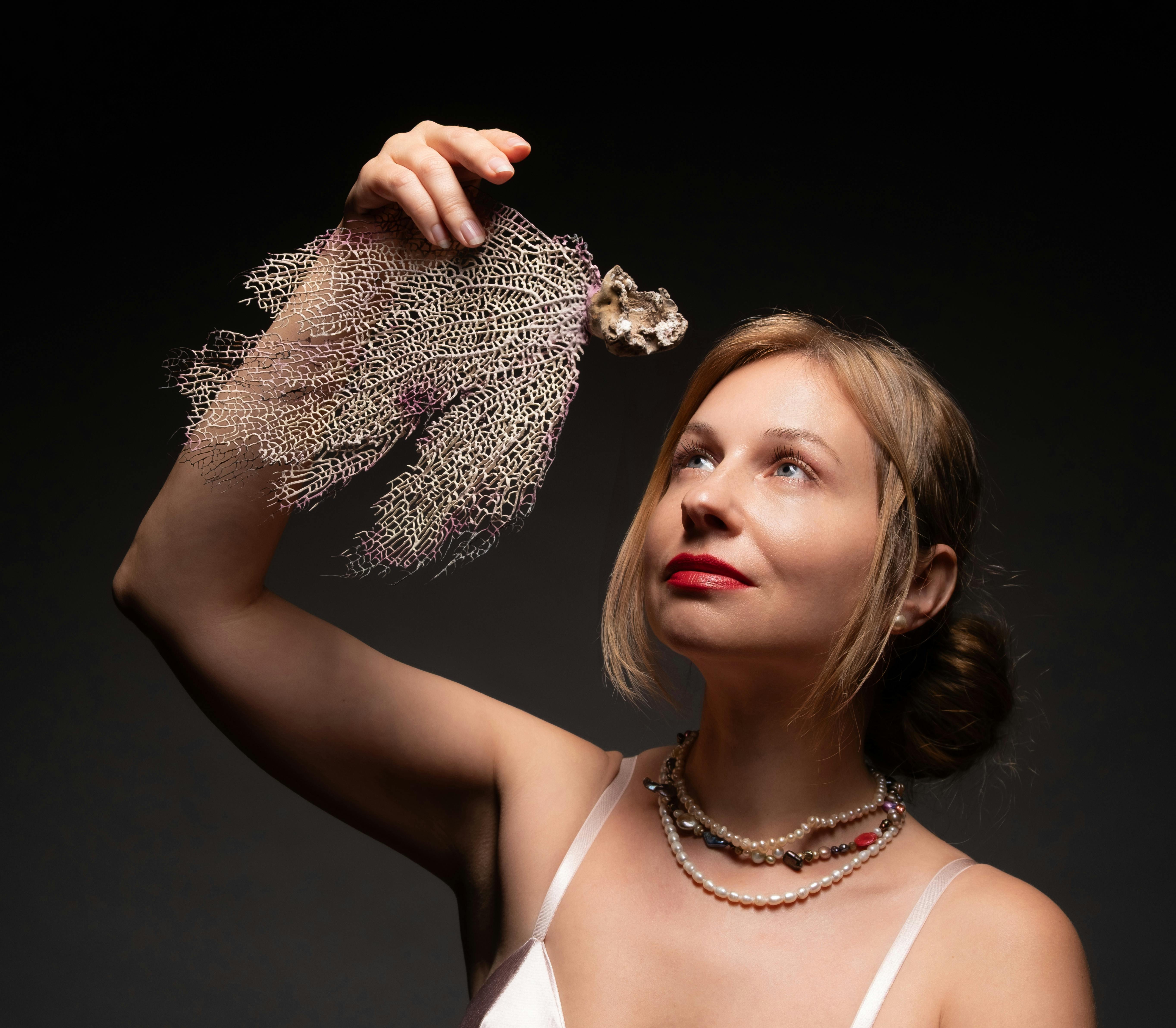 Ilmainen Muotokuva naisesta, jolla on meriviuhkakoralli studiovalaistuksen alla, esittelee eleganssia ja luonnollista kauneutta. Kuvapankkikuva