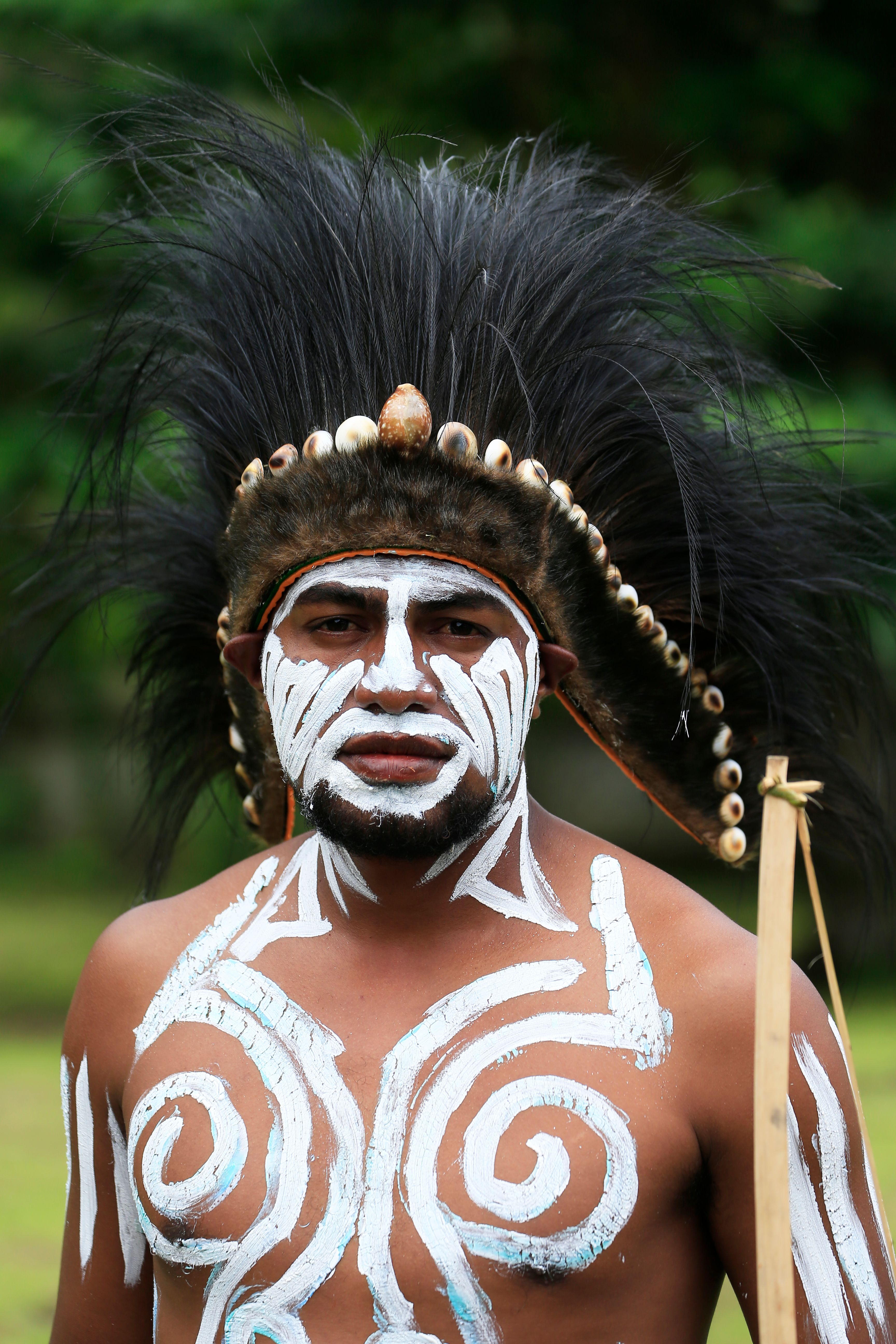 Portrait of a tribal man with face paint and elaborate headdress, showcasing cultural heritage.