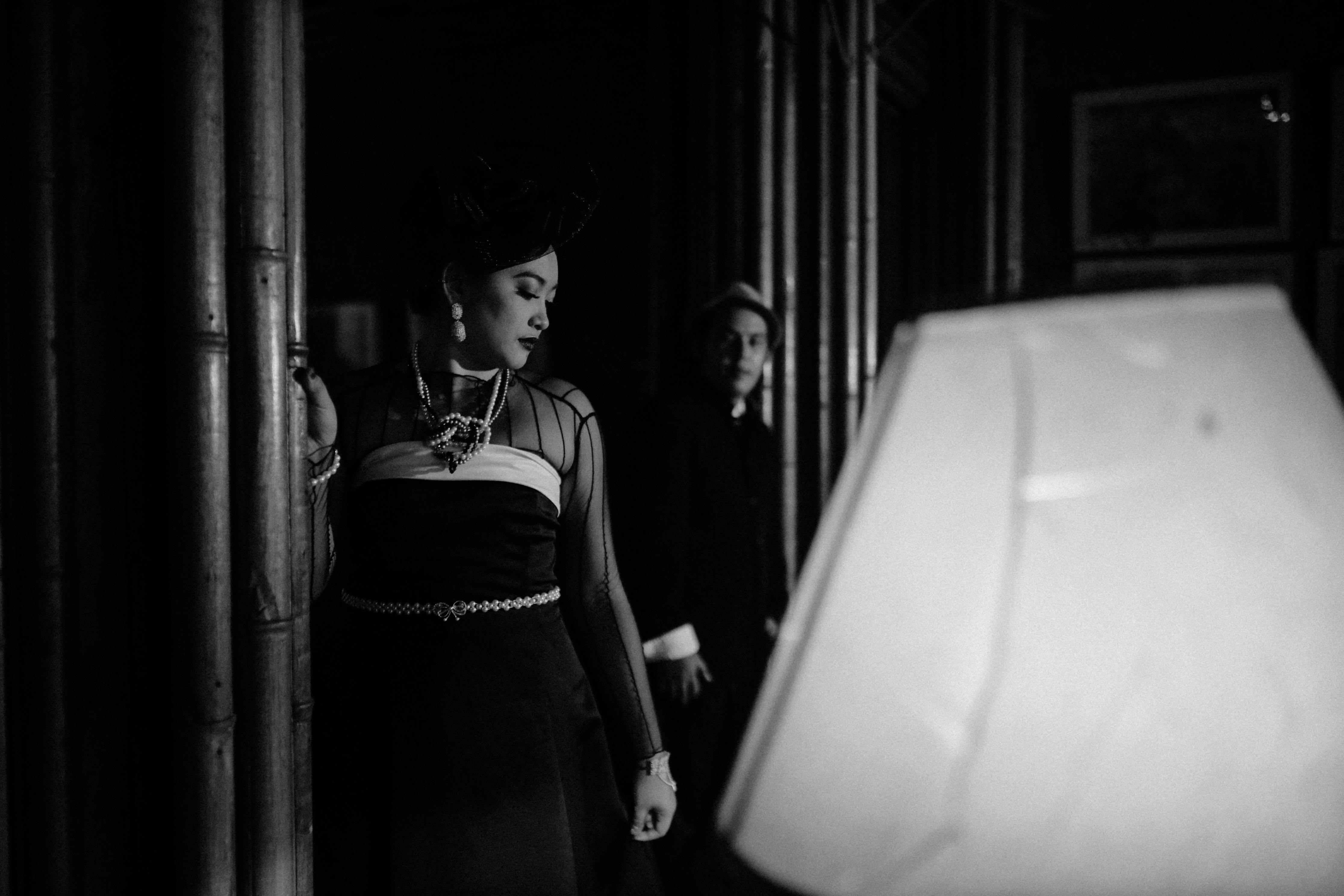 gratis Stijlvolle zwart-witfoto van een elegant gekleed stel in een schemerig verlichte kamer, met een vintage sfeer. Stockfoto