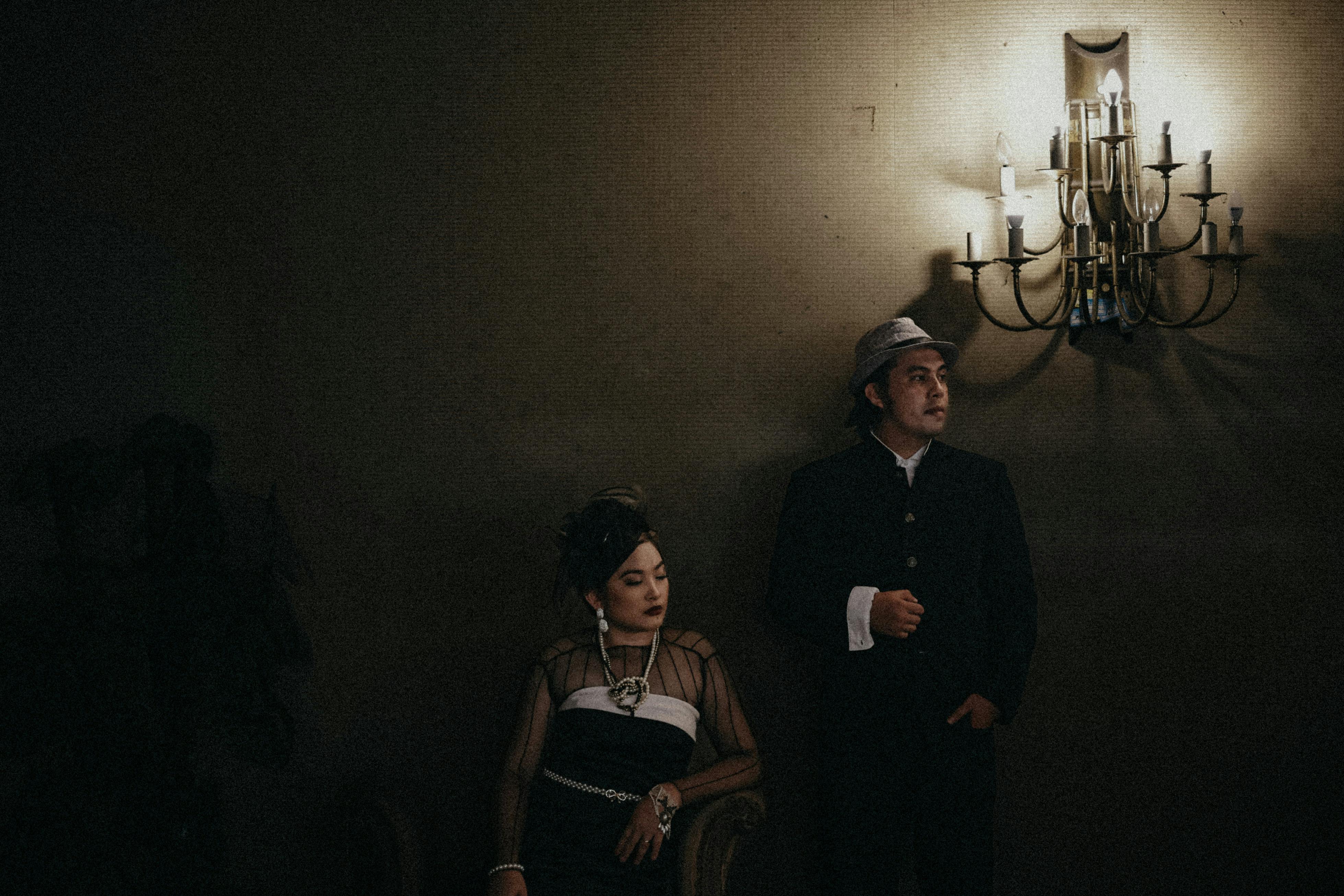 bezplatná Náladový portrét páru ve vintage stylu v tlumeně osvětlené místnosti s elegantním oblečením. Základová fotografie