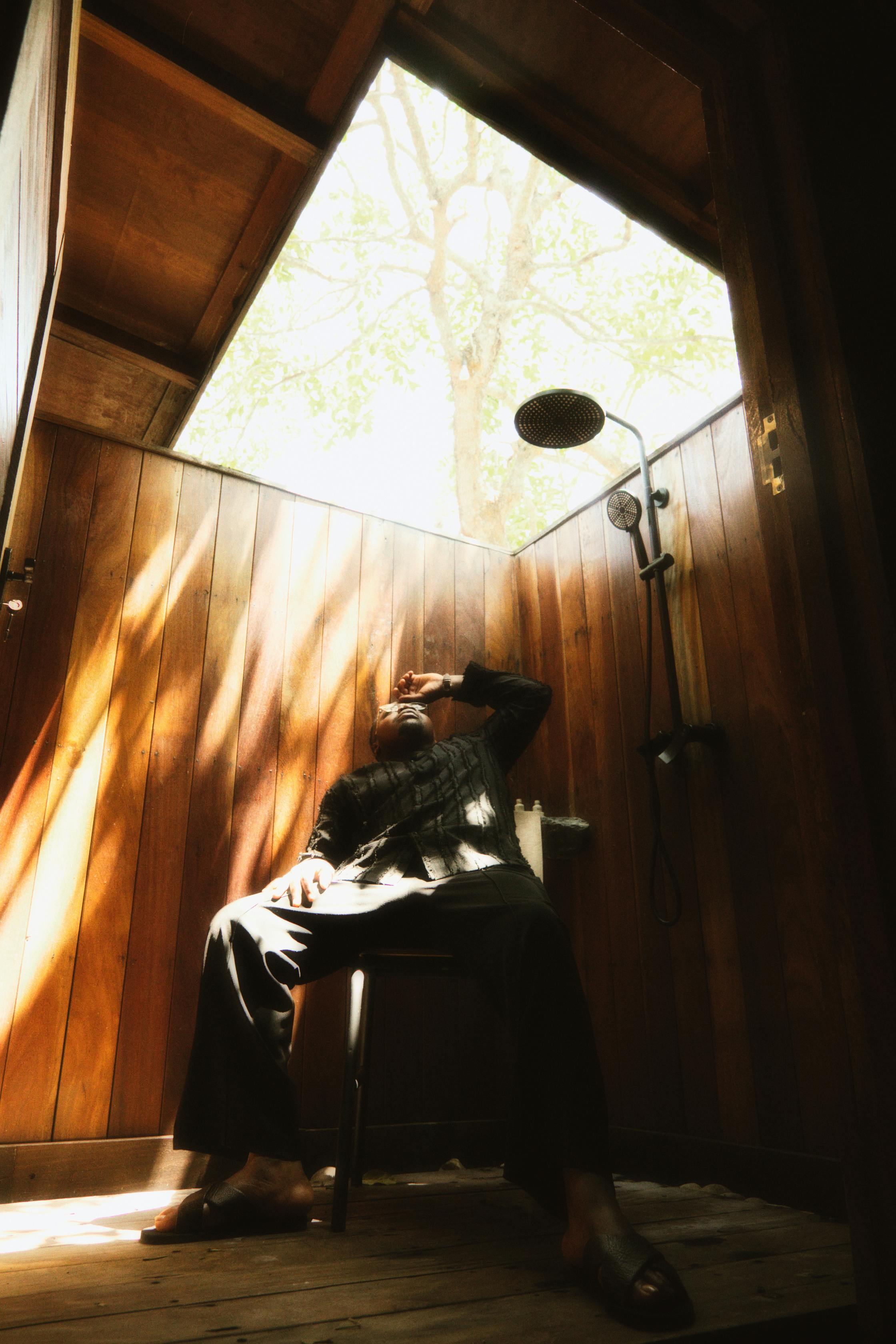 bezplatná Muž relaxuje v rustikální dřevěné venkovní sprše s přirozeným osvětlením v Adukromu v Ghaně. Základová fotografie