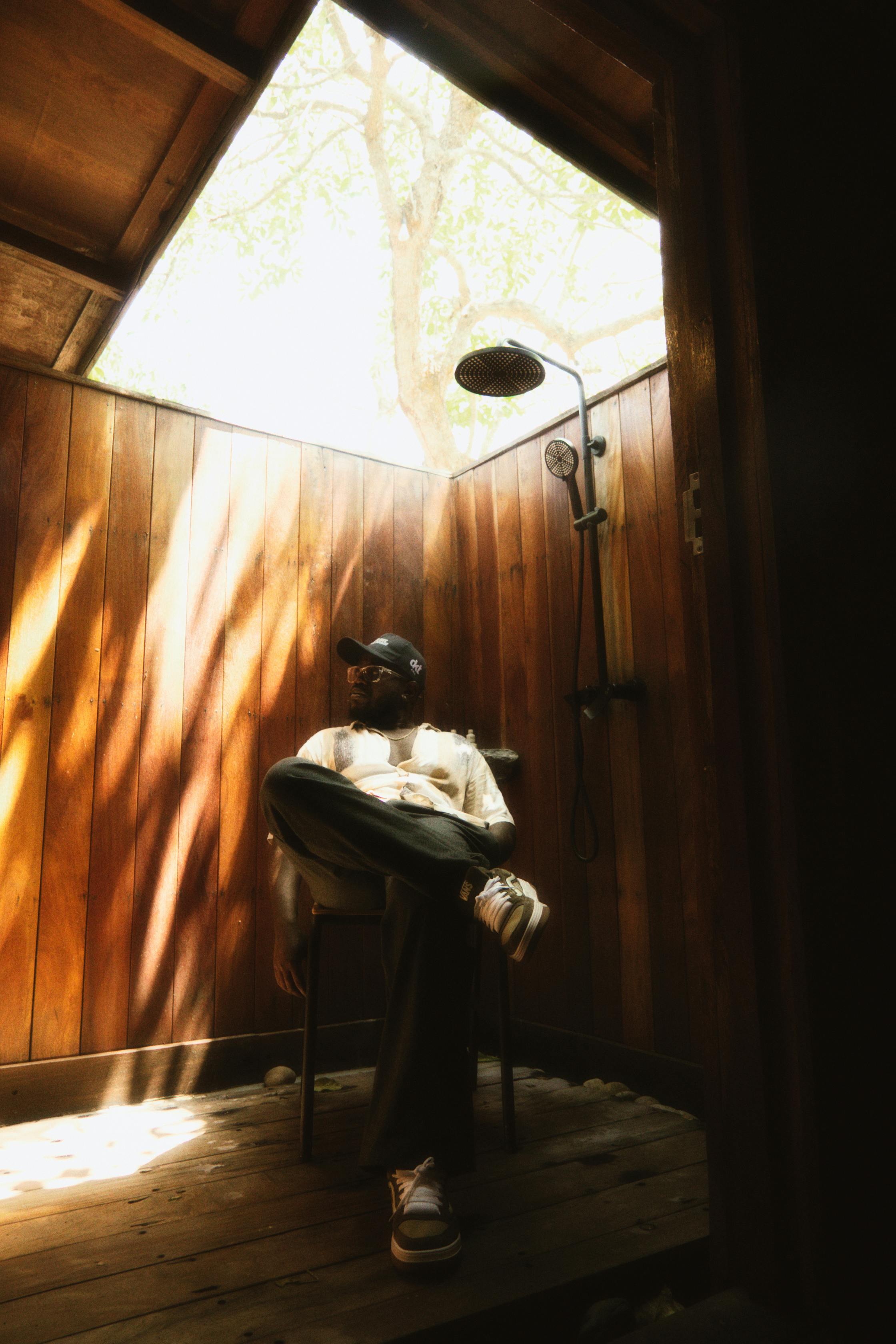 Ücretsiz Doğal ışığın süzüldüğü rustik ahşap duş alanında rahatlayan bir adam. Stok Fotoğraflar