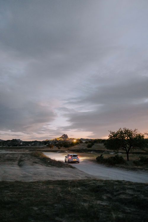 Free A car drives on a rural road during twilight in Cappadocia, Türkiye. Stock Photo