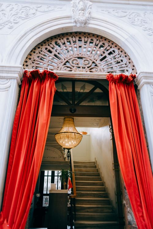 Free Grand entrance with red velvet curtains and ornate chandelier in a Turkish interior setting. Stock Photo