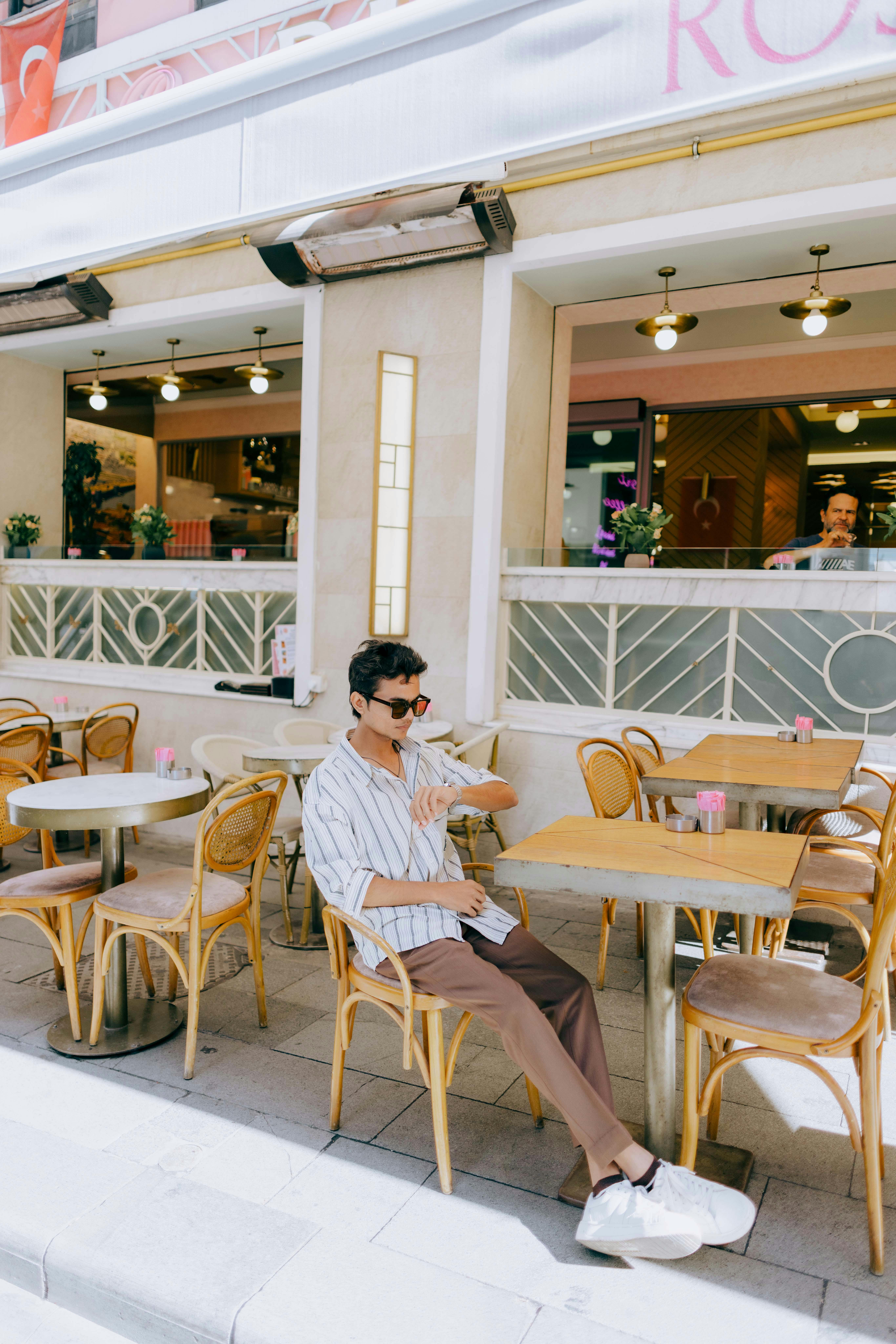 bezplatná Módní muž si užívá slunečný den v kavárně v Turecku, sedí venku. Základová fotografie
