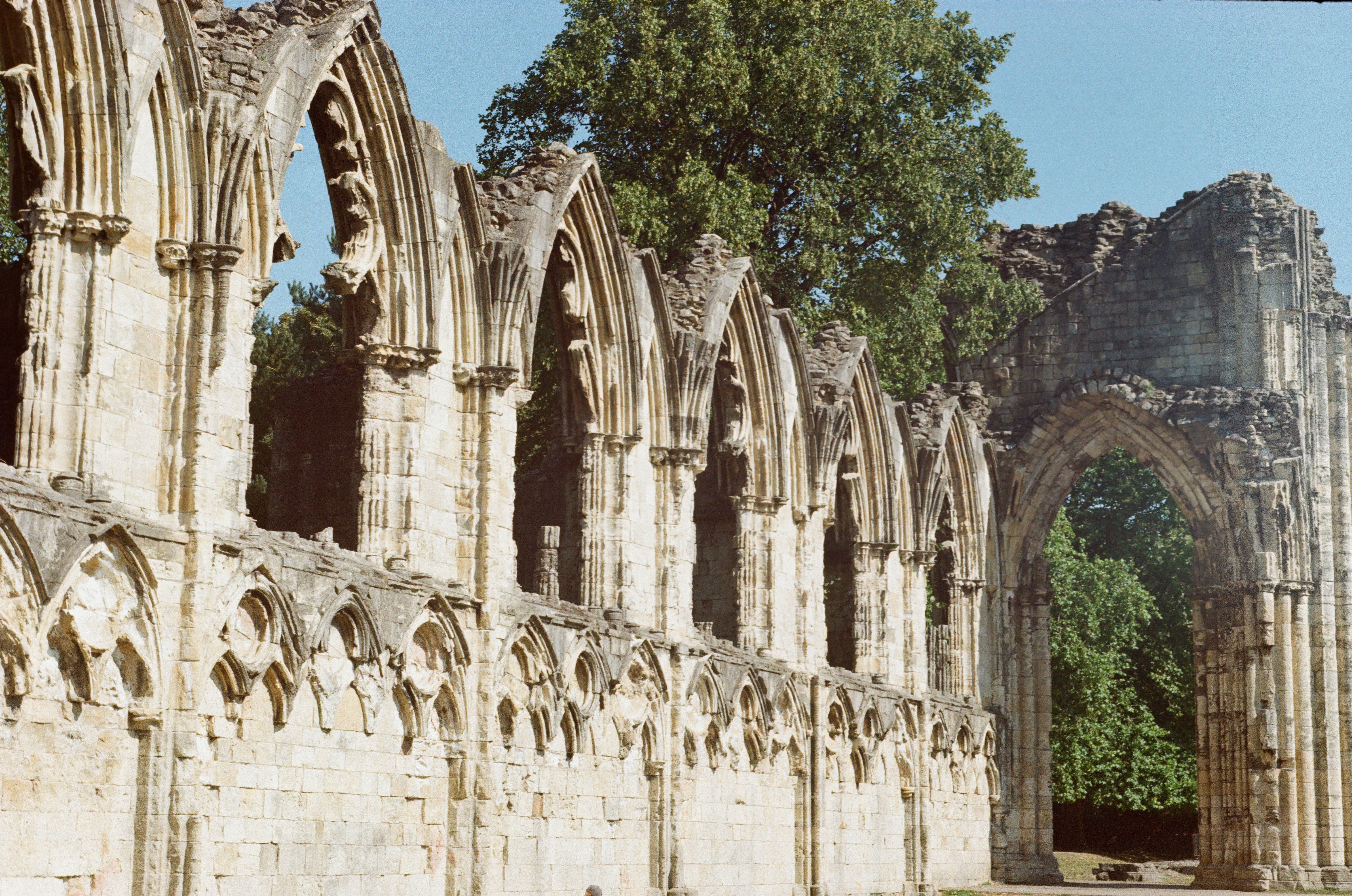 Historic stone arches of St Mary's Abbey ruins captured in York, England with lush greenery around. - Abbey de St. Gall