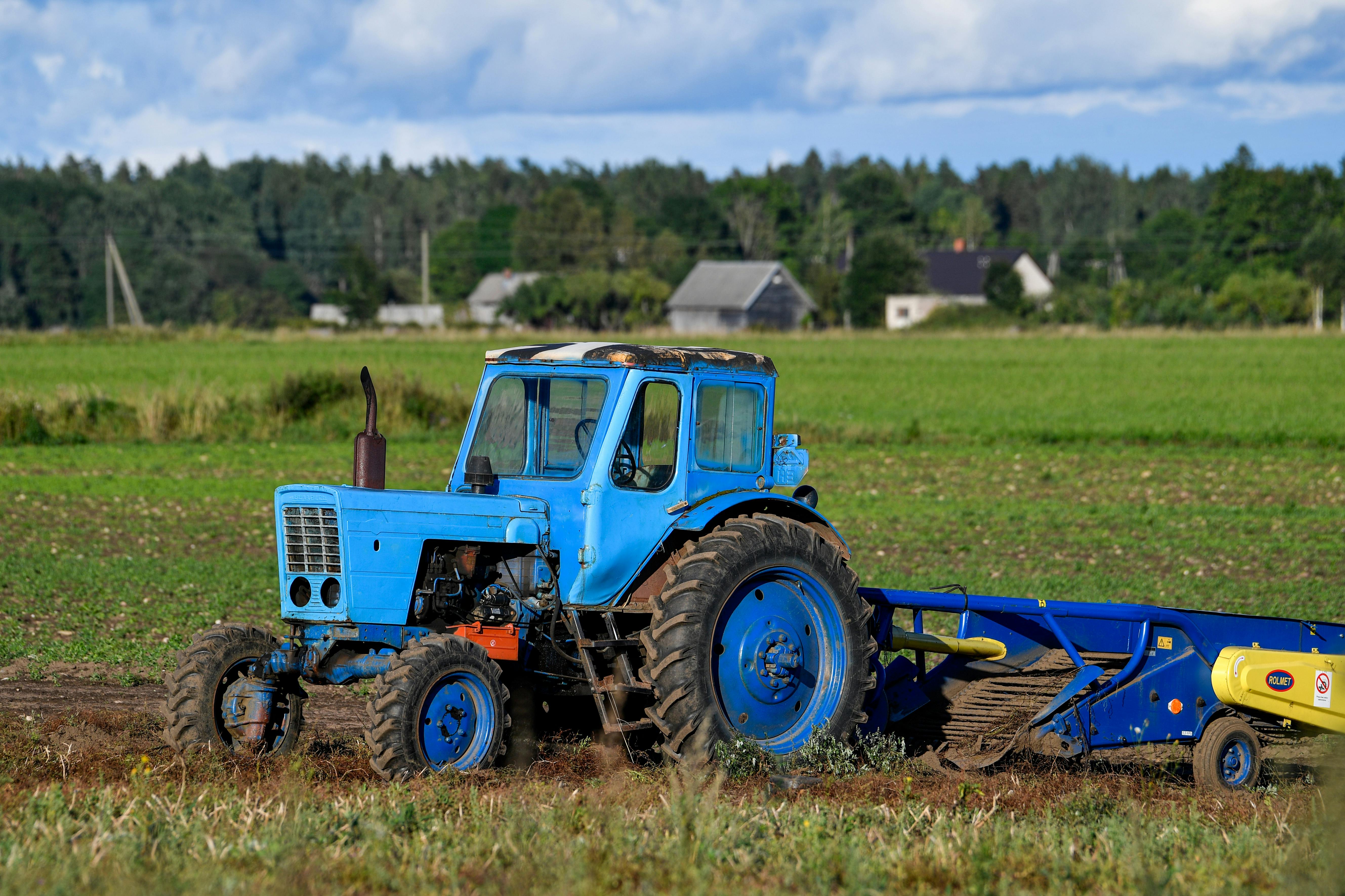 ฟรี รถแทรกเตอร์สีน้ำเงินคลาสสิกกำลังทำงานอยู่ในทุ่งหญ้าเขียวชอุ่มในเขตฮาร์จู ประเทศเอสโตเนีย คลังภาพถ่าย