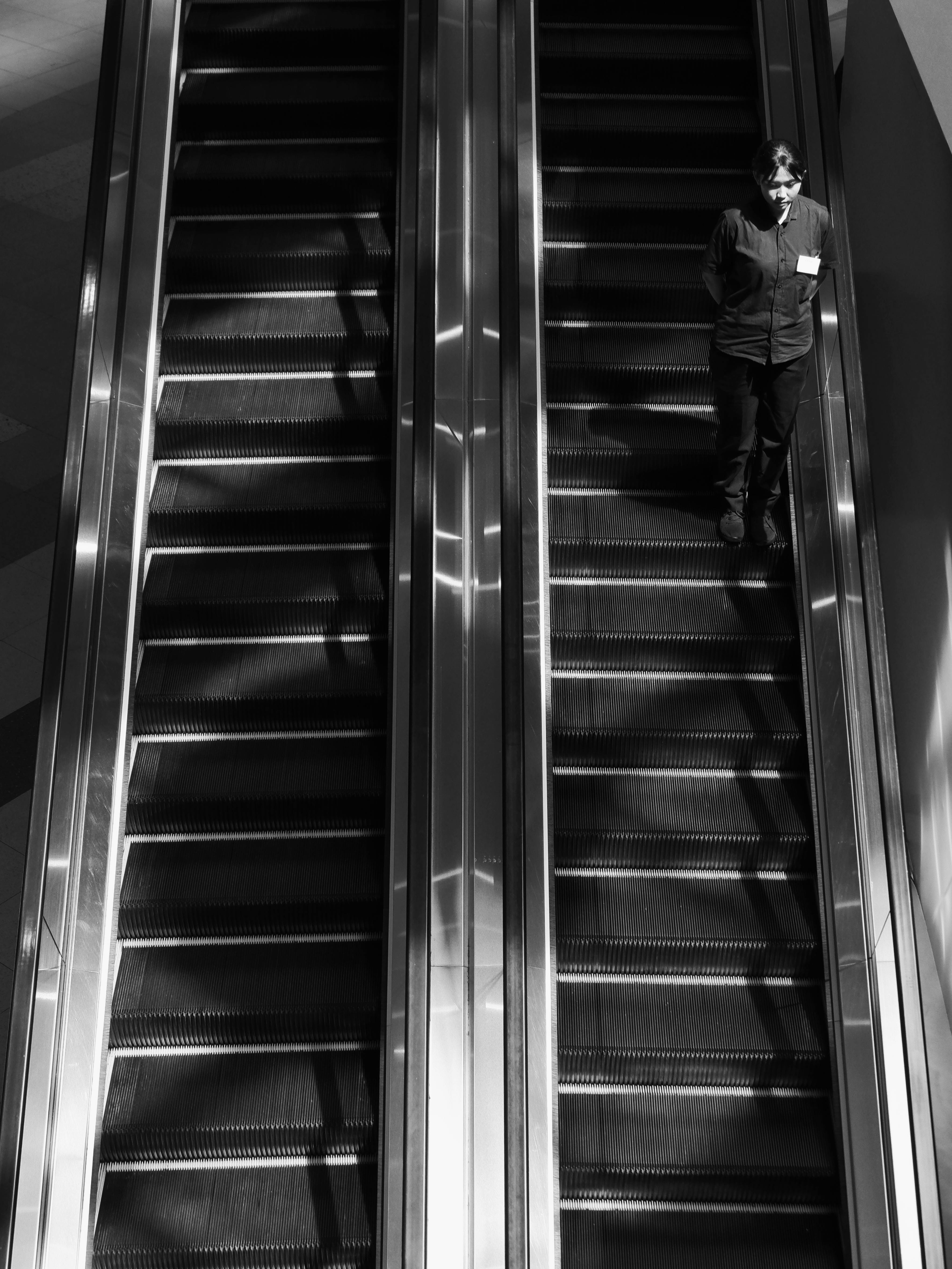 Free Monochrome scene with a lone man standing on an escalator in a department store. Stock Photo