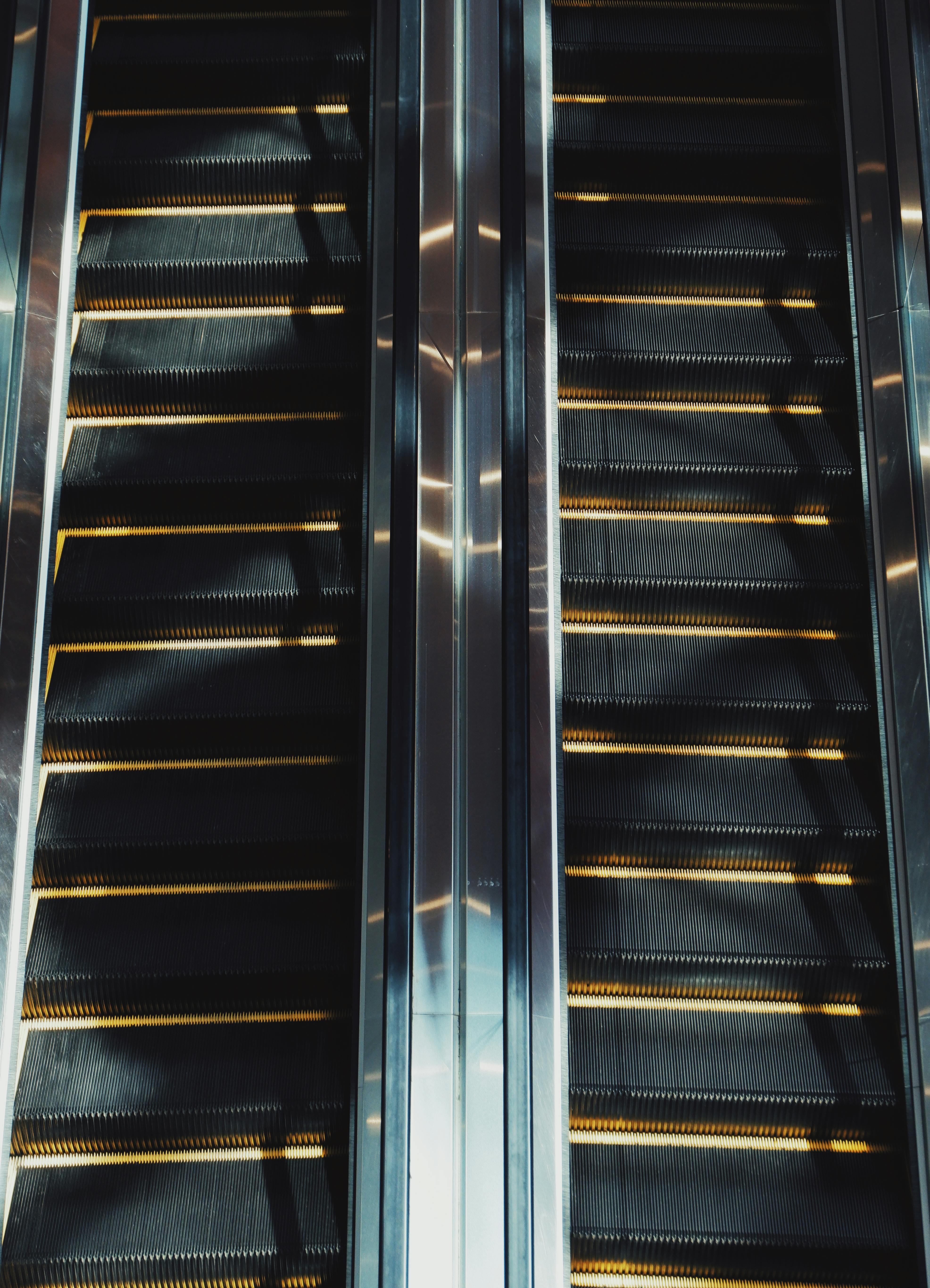 bezplatná Dvojice eskalátorů zachycená s výraznými kontrasty světla a stínu v interiéru. Základová fotografie