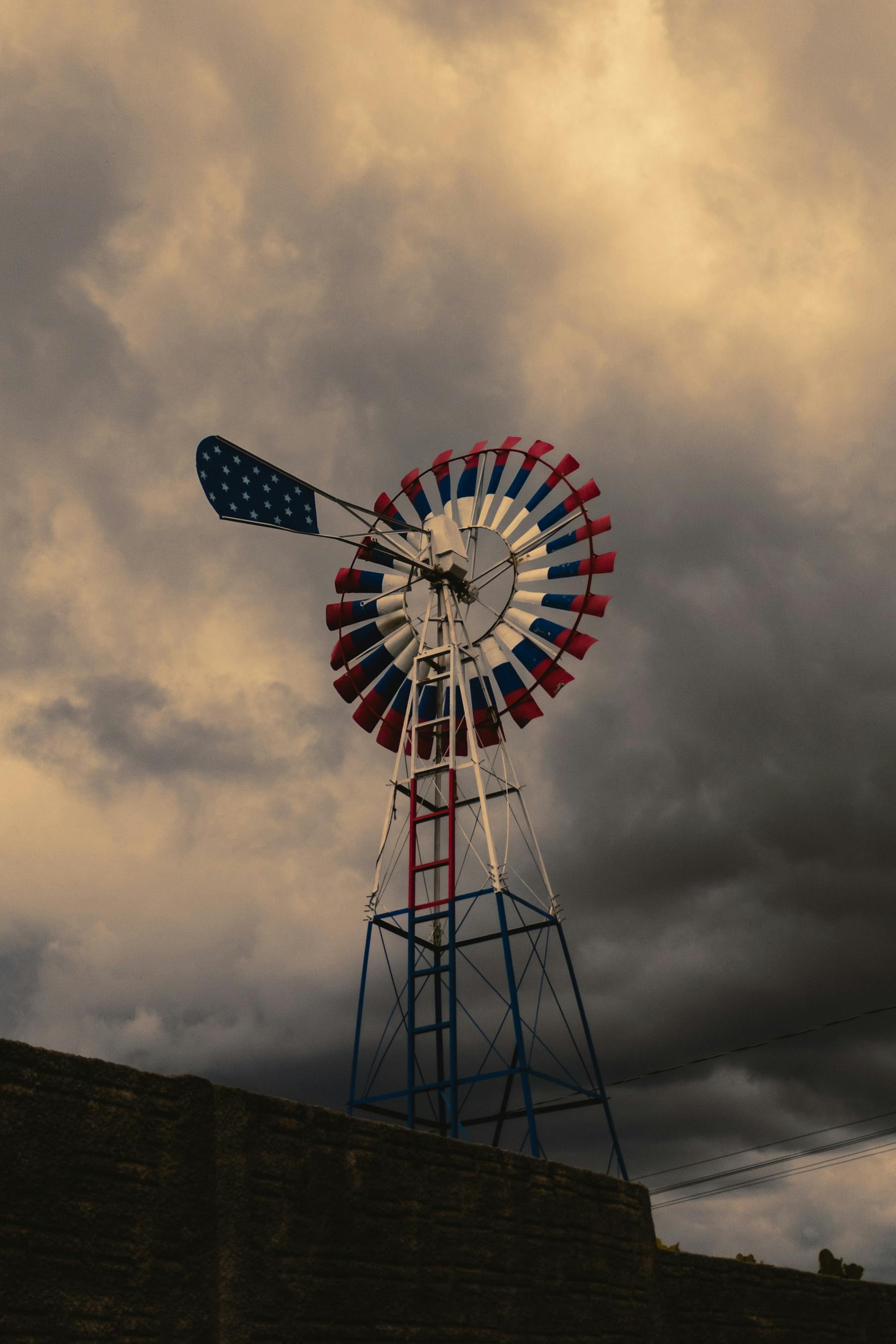 ฟรี กังหันลมสีแดง ขาว และน้ำเงิน ท่ามกลางเมฆพายุ สร้างภาพที่งดงามตระการตา คลังภาพถ่าย