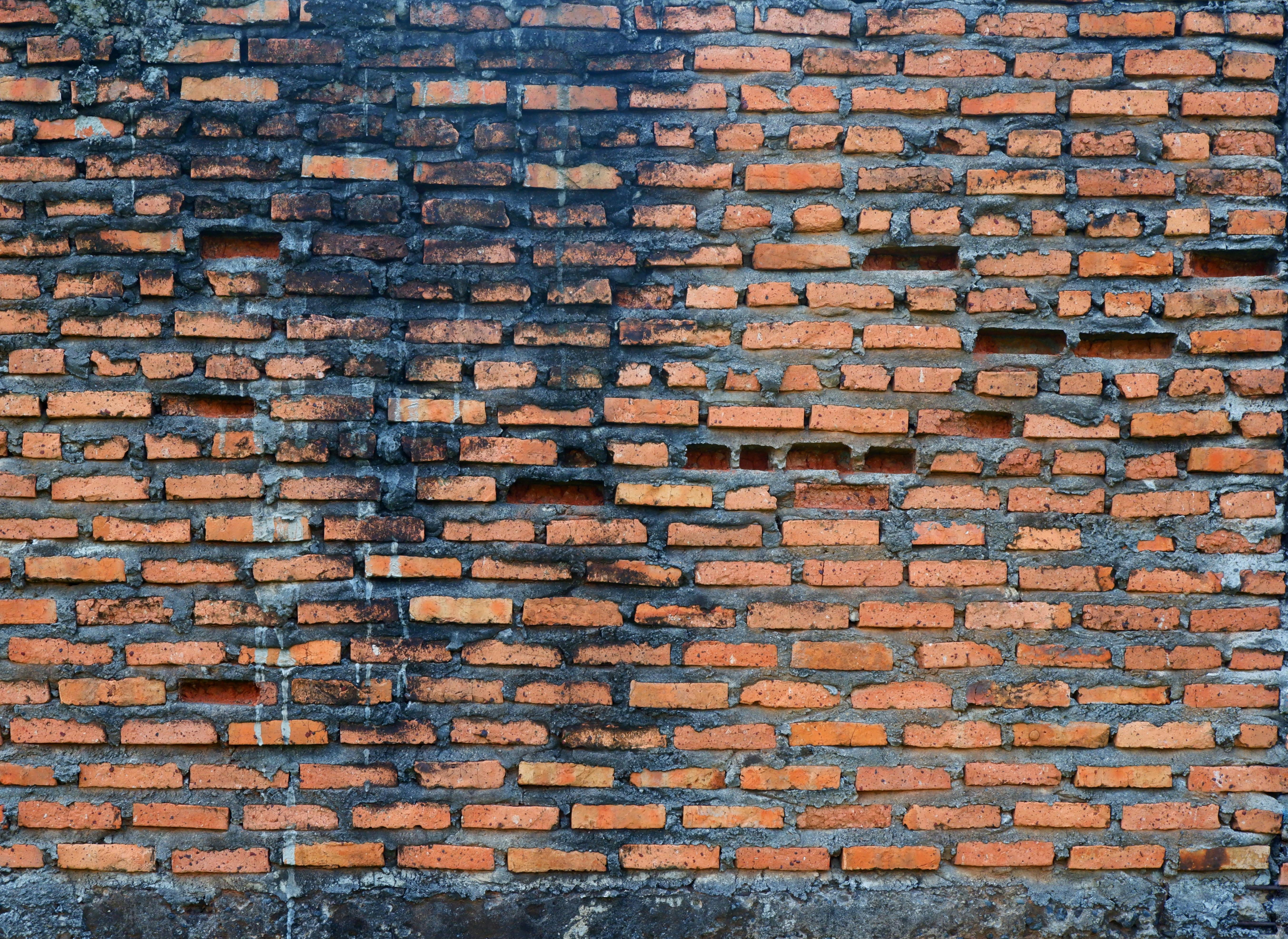 Gratis Primer plano de una pared de ladrillos rojos que muestra el desgaste y la textura. Foto de stock