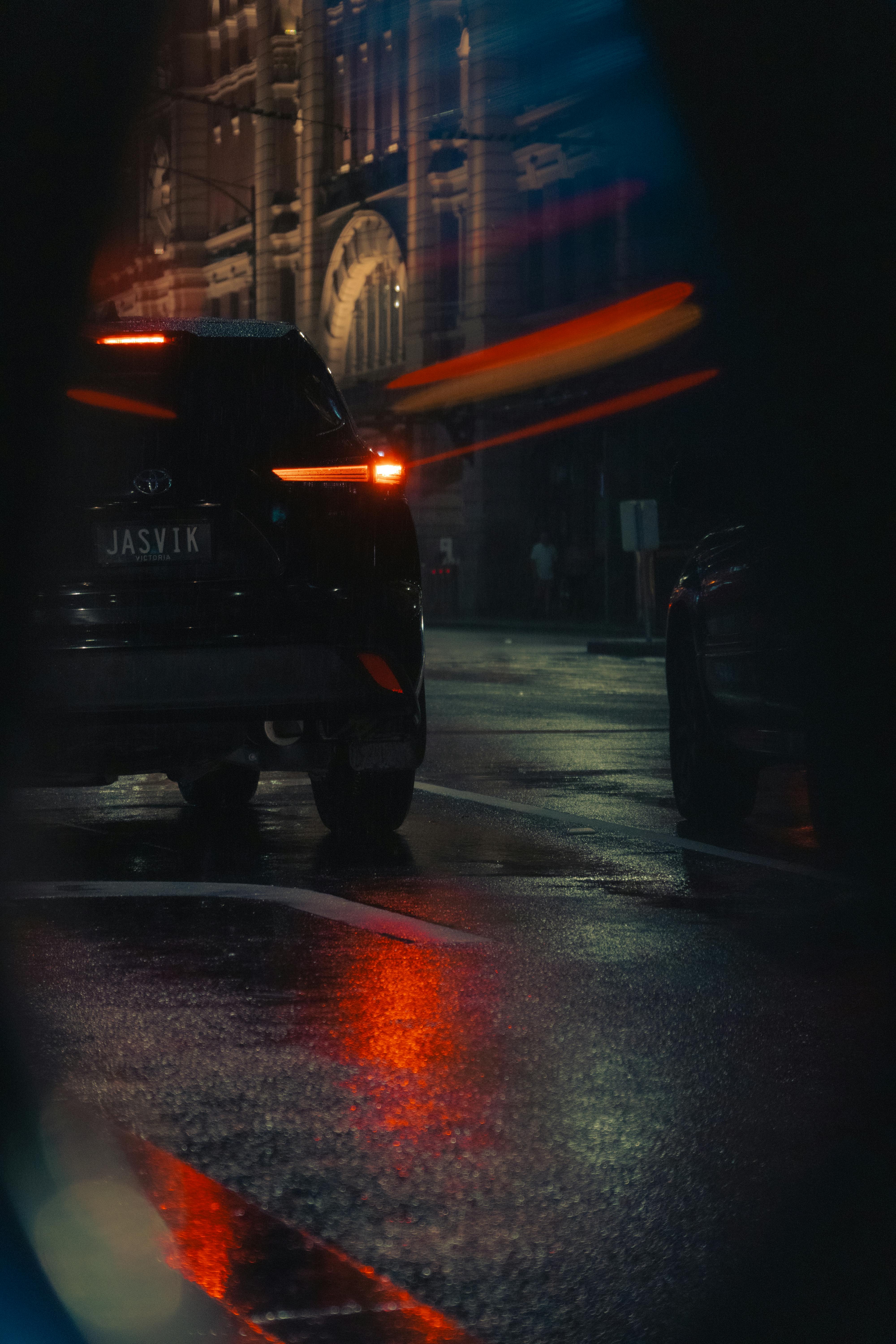grátis Cena noturna melancólica de rua em Melbourne, com um carro e reflexos vibrantes. Foto profissional