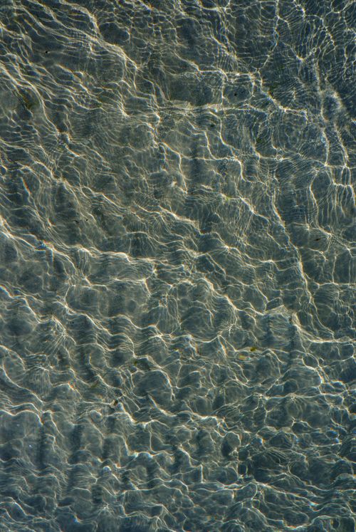 Free A captivating close-up of sunlight casting ripples on clear water, creating a mesmerizing texture. Stock Photo
