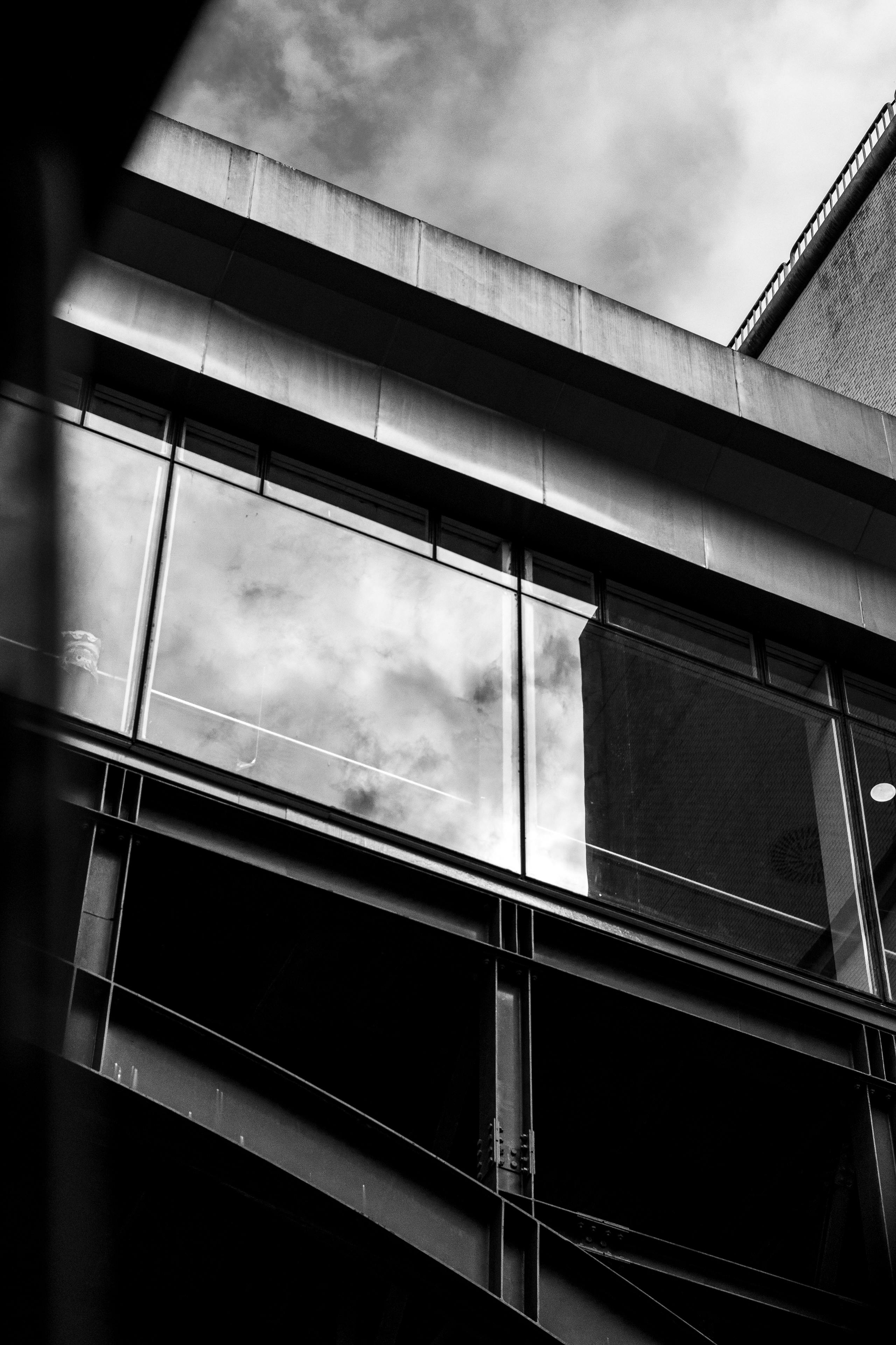 Free Black and white photo of a modern building with reflective glass and urban architecture. Stock Photo