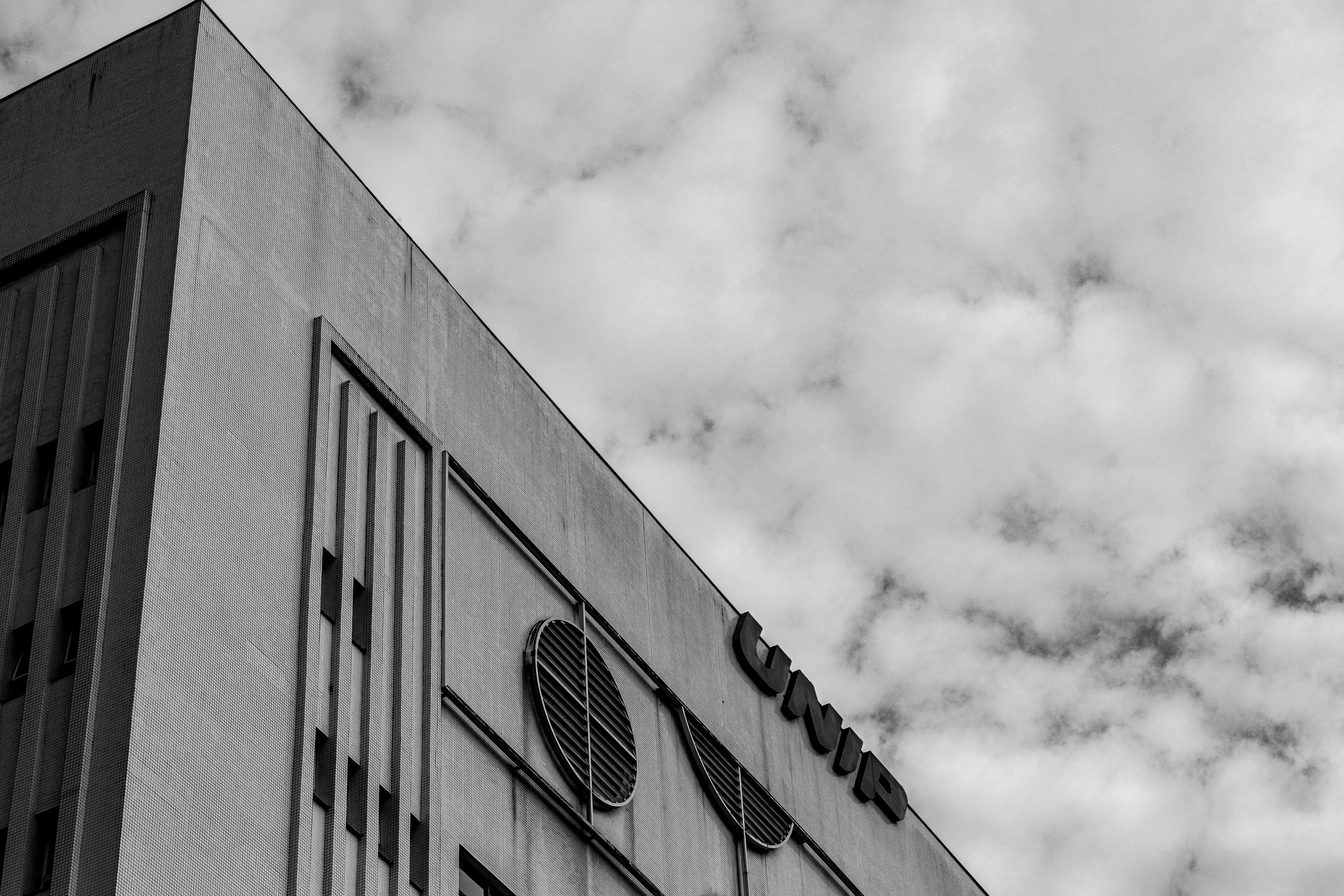 Zadarmo Čiernobiela fotografia fasády modernej mestskej budovy s oblakmi nad hlavou. Fotka z fotobanky