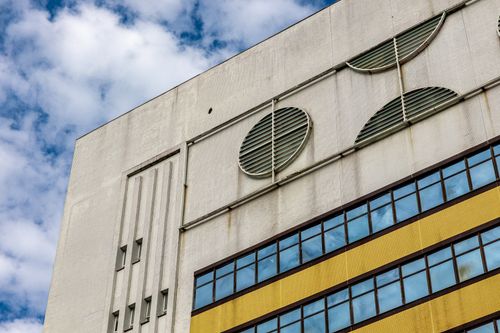 Free Contemporary building facade showing geometric patterns and urban design elements under a cloudy sky. Stock Photo