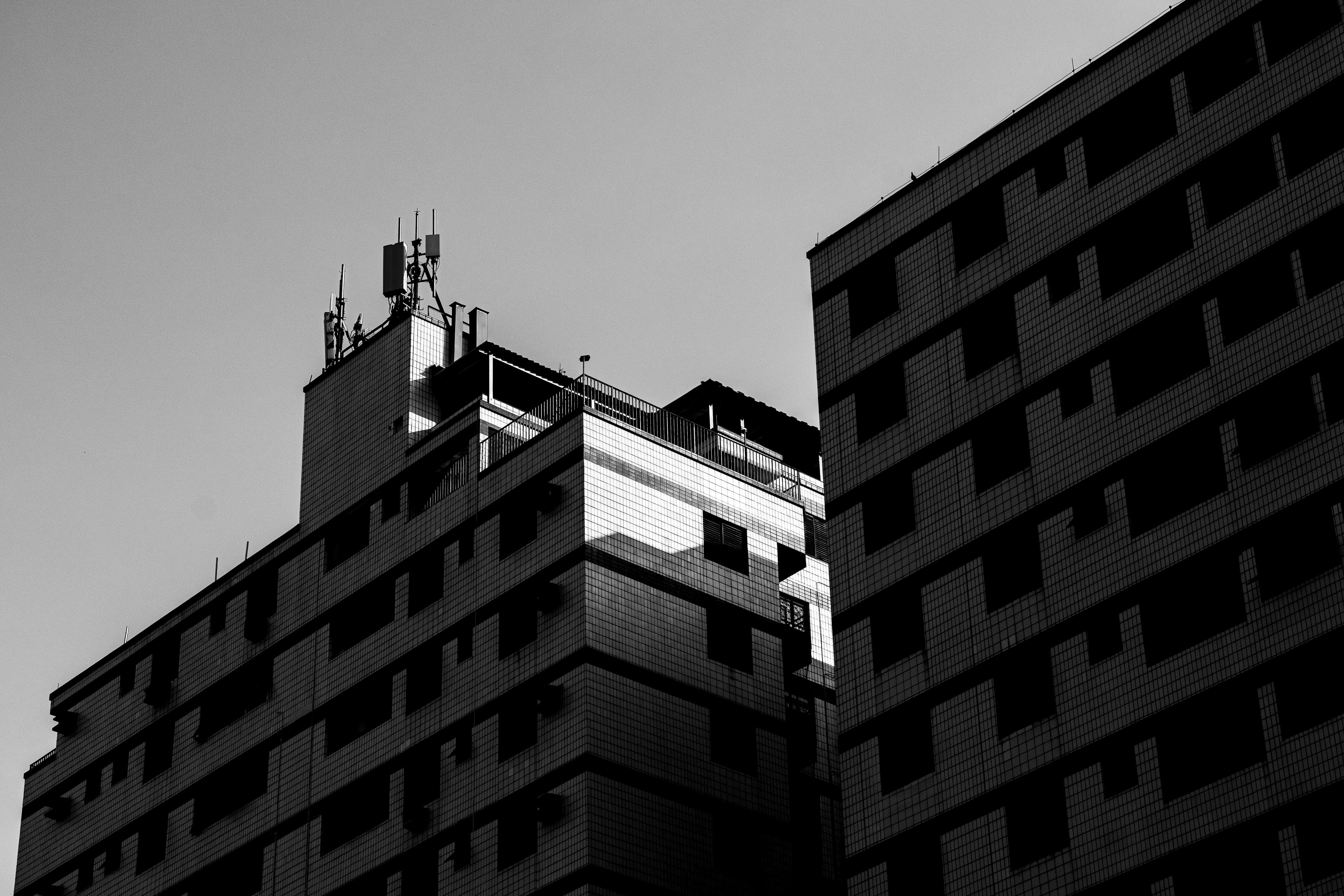 Kostnadsfria Svartvitt foto av en geometrisk fasad på en höghusbyggnad med modern arkitektur och urban känsla. Stock foto