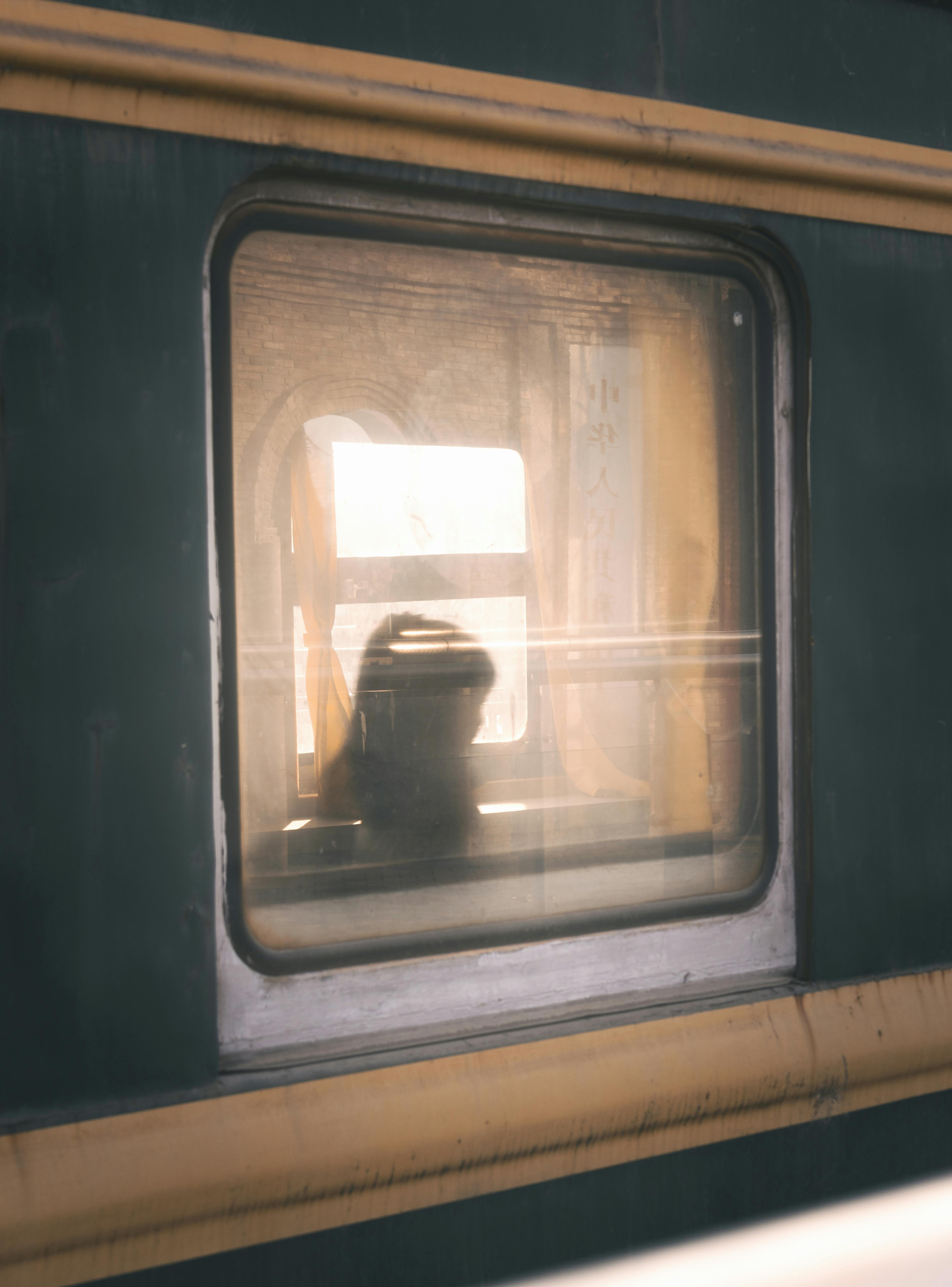 Ücretsiz Gün batımı sırasında tren penceresinden görünen bir kişinin silueti, yolculuğu ve içe dönüklüğü yansıtıyor. Stok Fotoğraflar