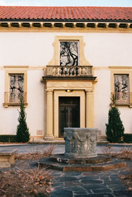 A classic facade of a historical building with a detailed courtyard fountain.