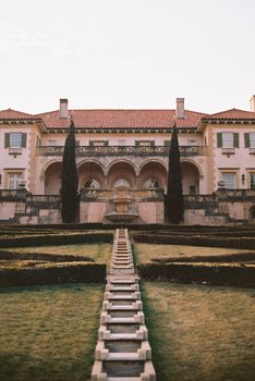 Elegant mansion with manicured gardens and fountain, capturing classic European architecture at sunset.