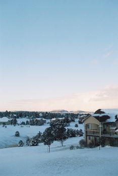 Scenic snowy landscape featuring modern house at sunset.