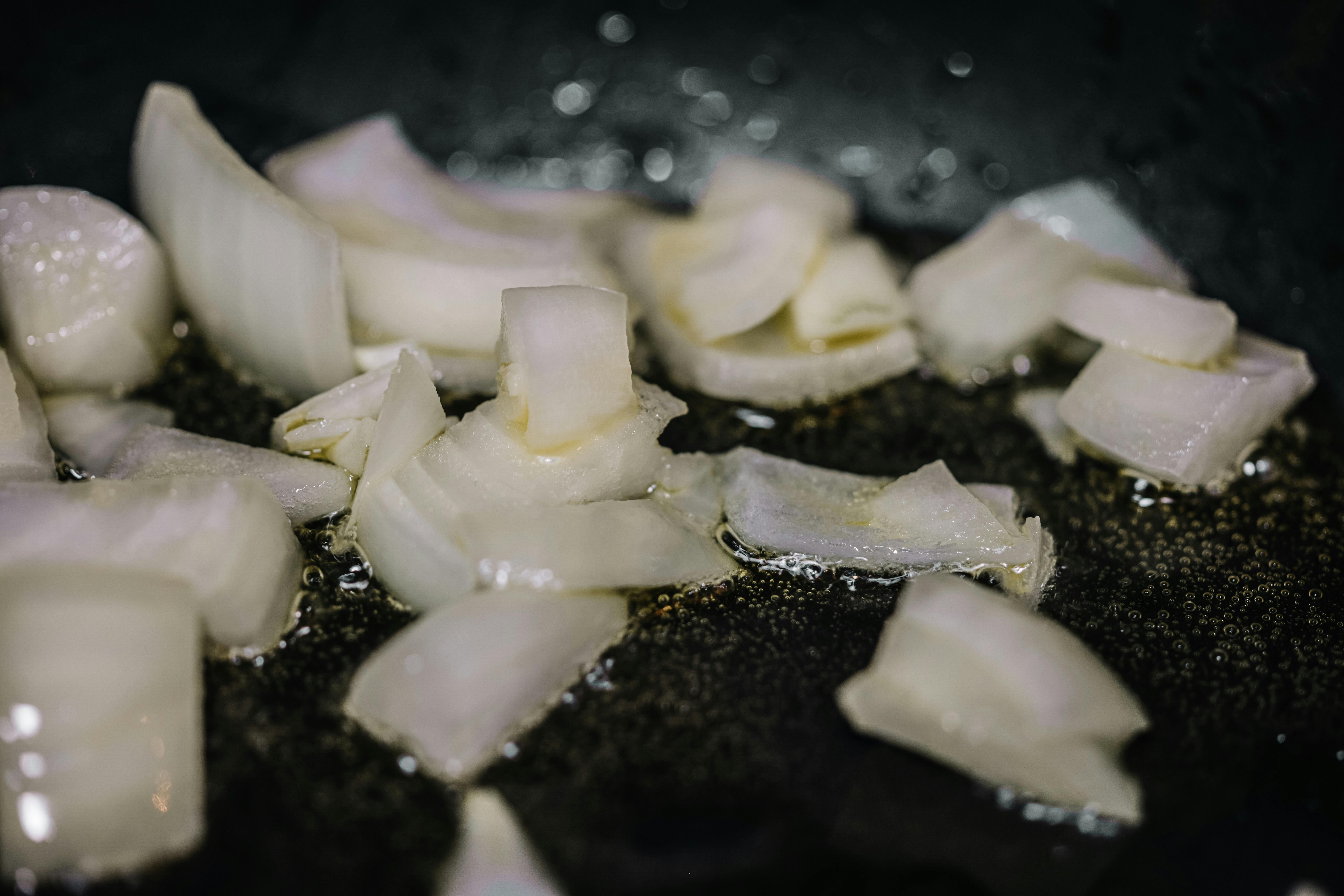 Close-up of chopped onions sizzling in oil in a frying pan, perfect for cooking blogs.