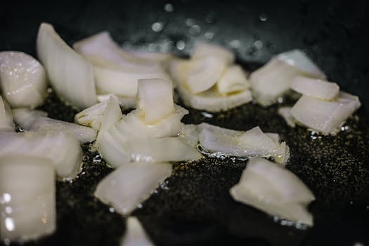 Close-up of chopped onions sizzling in oil in a frying pan, perfect for cooking blogs.