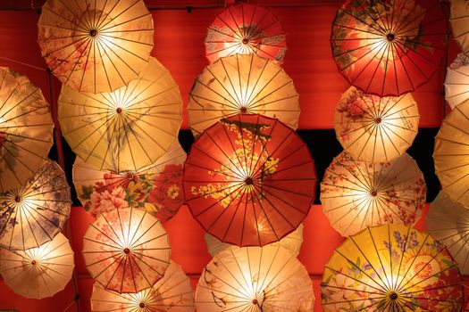 Vibrant assortment of illuminated Asian-style umbrellas with intricate floral patterns, creating a stunning decorative display.