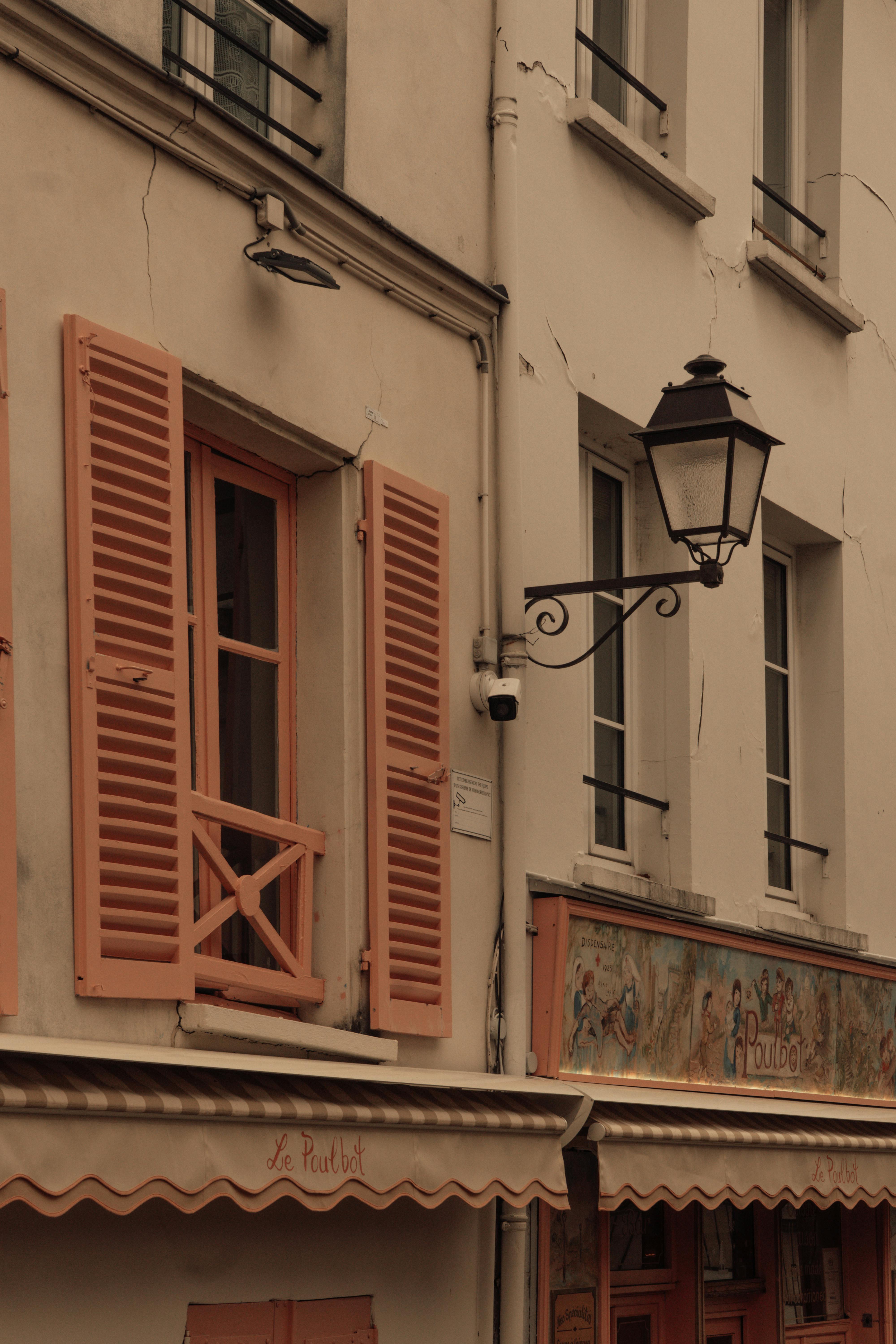 Bezpłatne Odkryj historyczną paryską ulicę z charakterystycznymi brzoskwiniowymi okiennicami i zabytkową latarnią uliczną. Zdjęcie z galerii