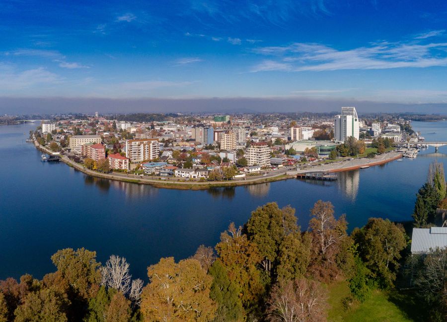 A stunning aerial view of a city island surrounded by a calm river under a bright blue sky.