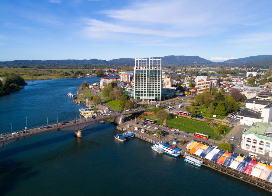 Aerial view of Valdivia, Chile, showcasing the river, bridge, and modern architecture.