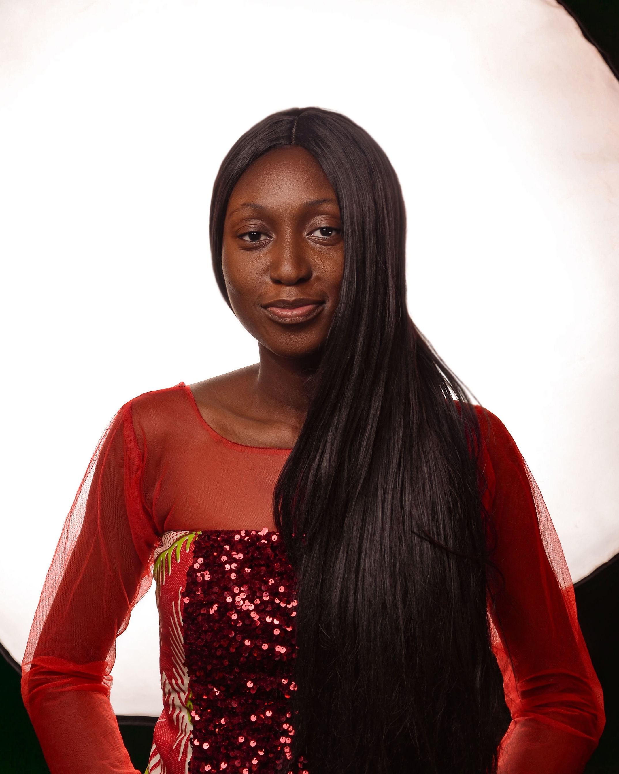 Stylish portrait of a woman in a red embellished dress against a soft backdrop.