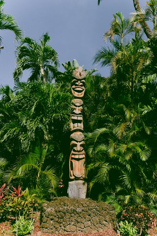 Free Tiki statue surrounded by lush tropical plants in a Hawaii garden setting. Stock Photo
