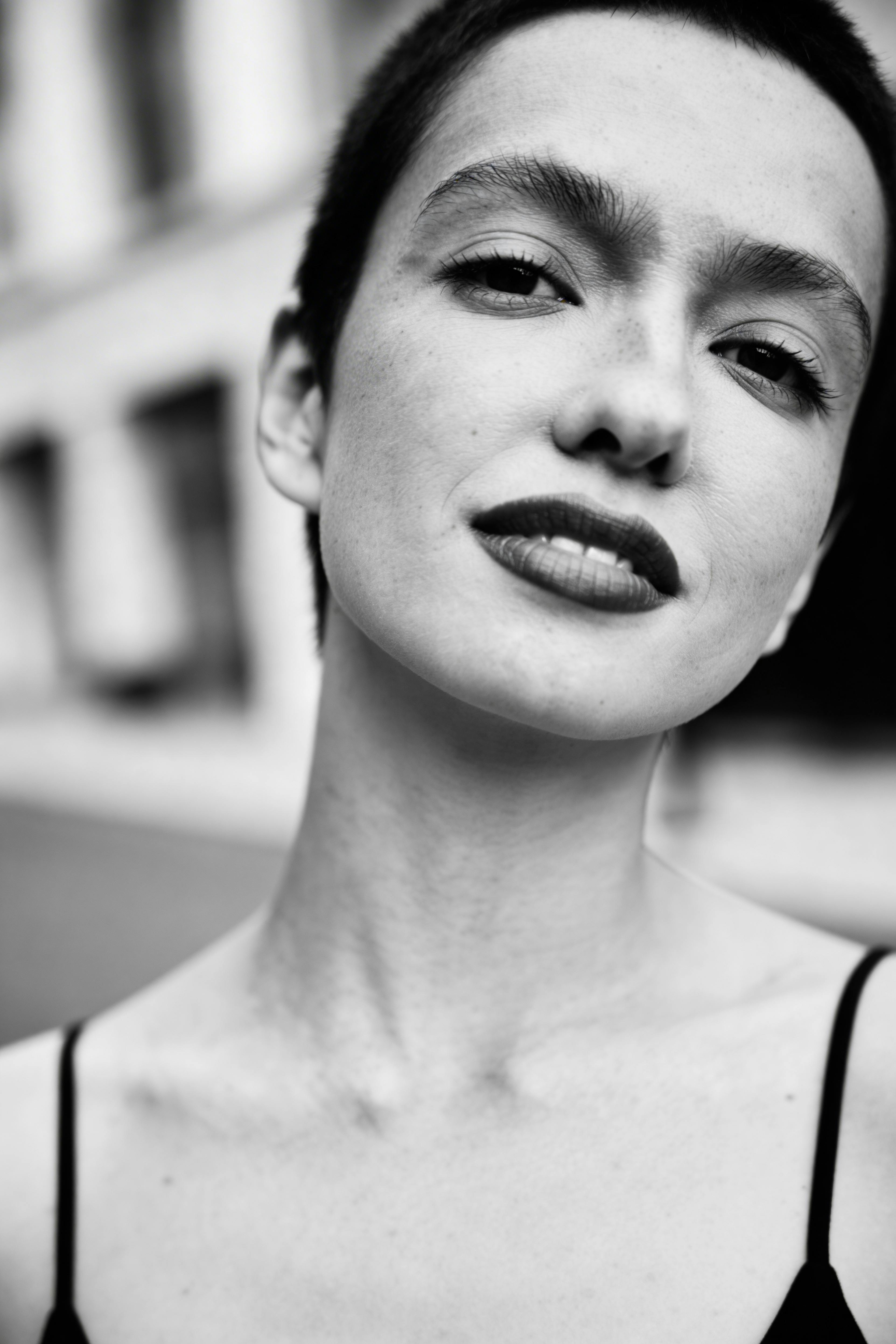Artistic black and white portrait capturing the expressive face of a young woman with natural light.