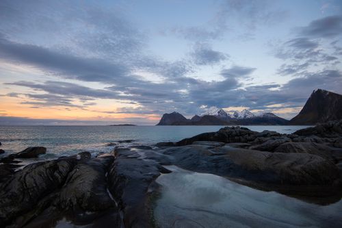 Free Scenic view of rocky coastline with mountains and ocean at sunset. Stock Photo