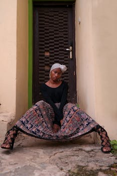 一位头戴头巾、身着印花裙的时尚女子在门口摆出姿势
