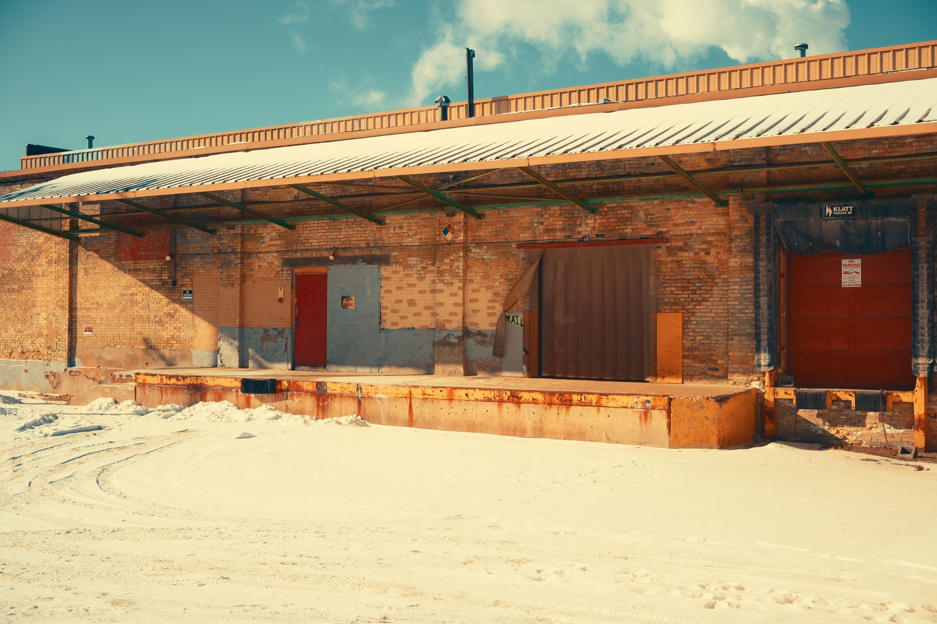 Metal industrial warehouse building with a snow-covered roof and grounds in winter