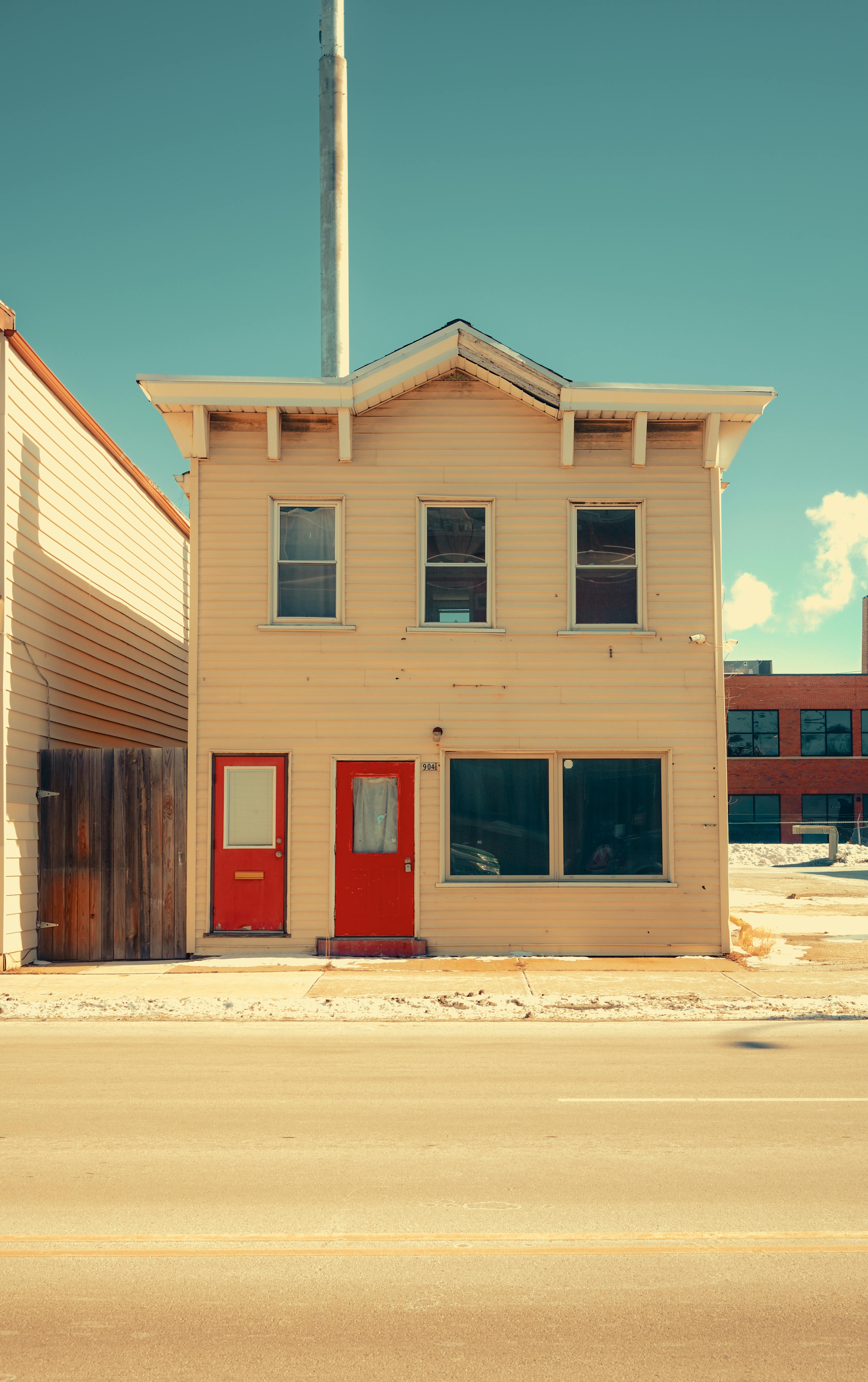 Kostnadsfria Charmigt tvåvåningshus med röda dörrar och gammaldags arkitektur på en solig dag. Stock foto