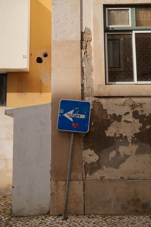 Free A weathered wall with a leaning traffic sign in Lisbon, Portugal. Stock Photo