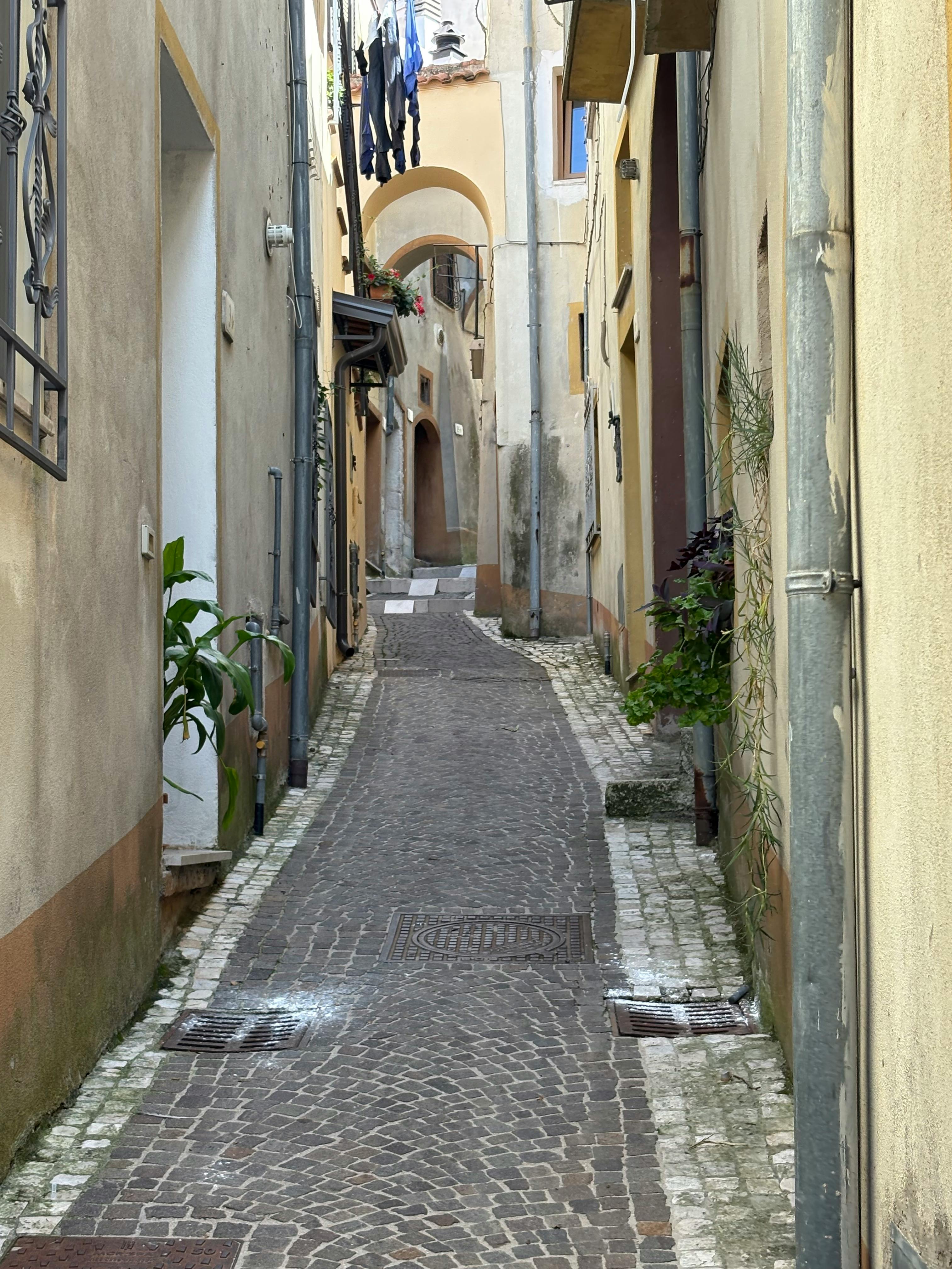 Gratis Scopri una pittoresca strada acciottolata in un incantevole villaggio italiano, perfetta per le passeggiate. Foto a disposizione